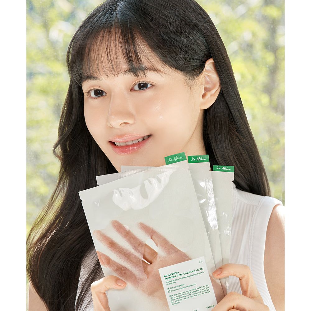 Frau hält mehrere Packungen der Dr. Althea Cushion Veil Beruhigende Maske. Die Verpackung ist weiß mit grünen Akzenten.