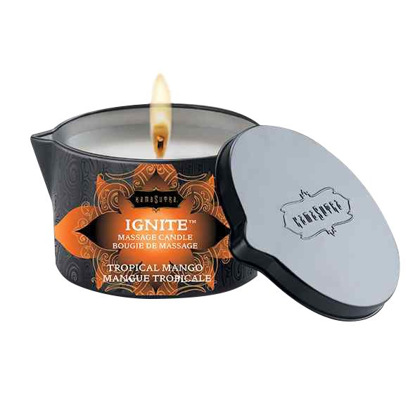Massagekerze mit Deckel. Schwarzer Behälter mit orangefarbenem Etikett. Aufschrift: Kamasutra, Ignite, Tropical Mango. Brennende Flamme.