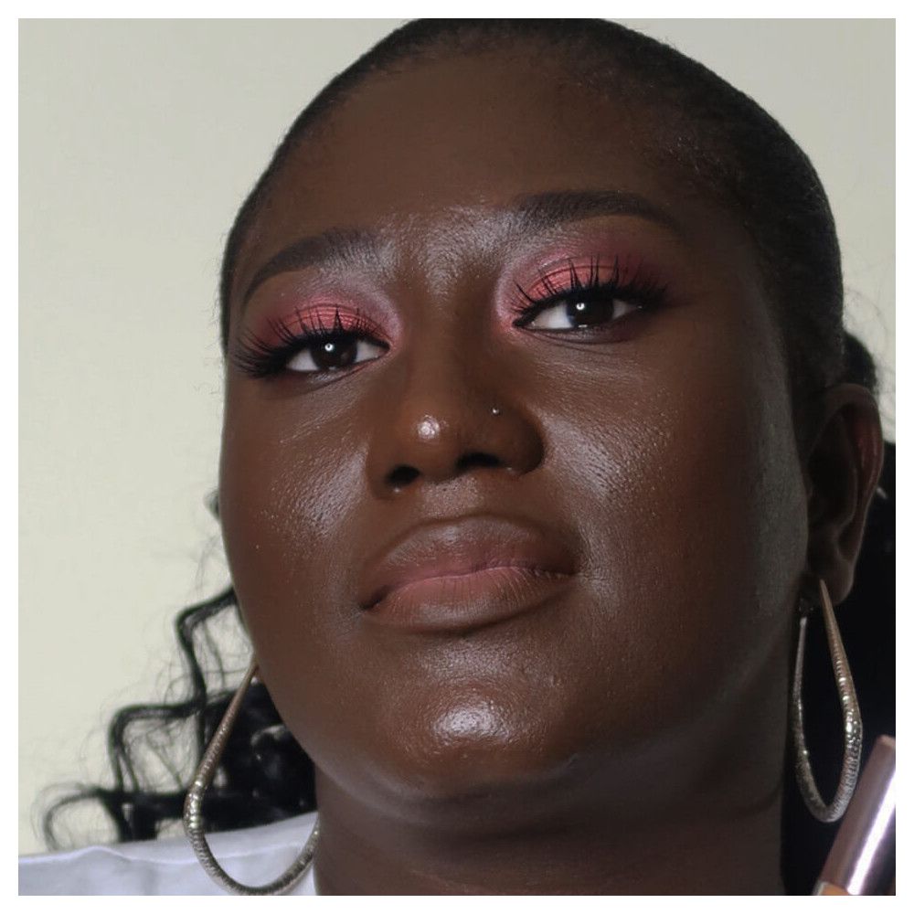 Dunkelhäutige Frau mit Make-up. Rosa Lidschatten, Lippenstift. Große Creolen.