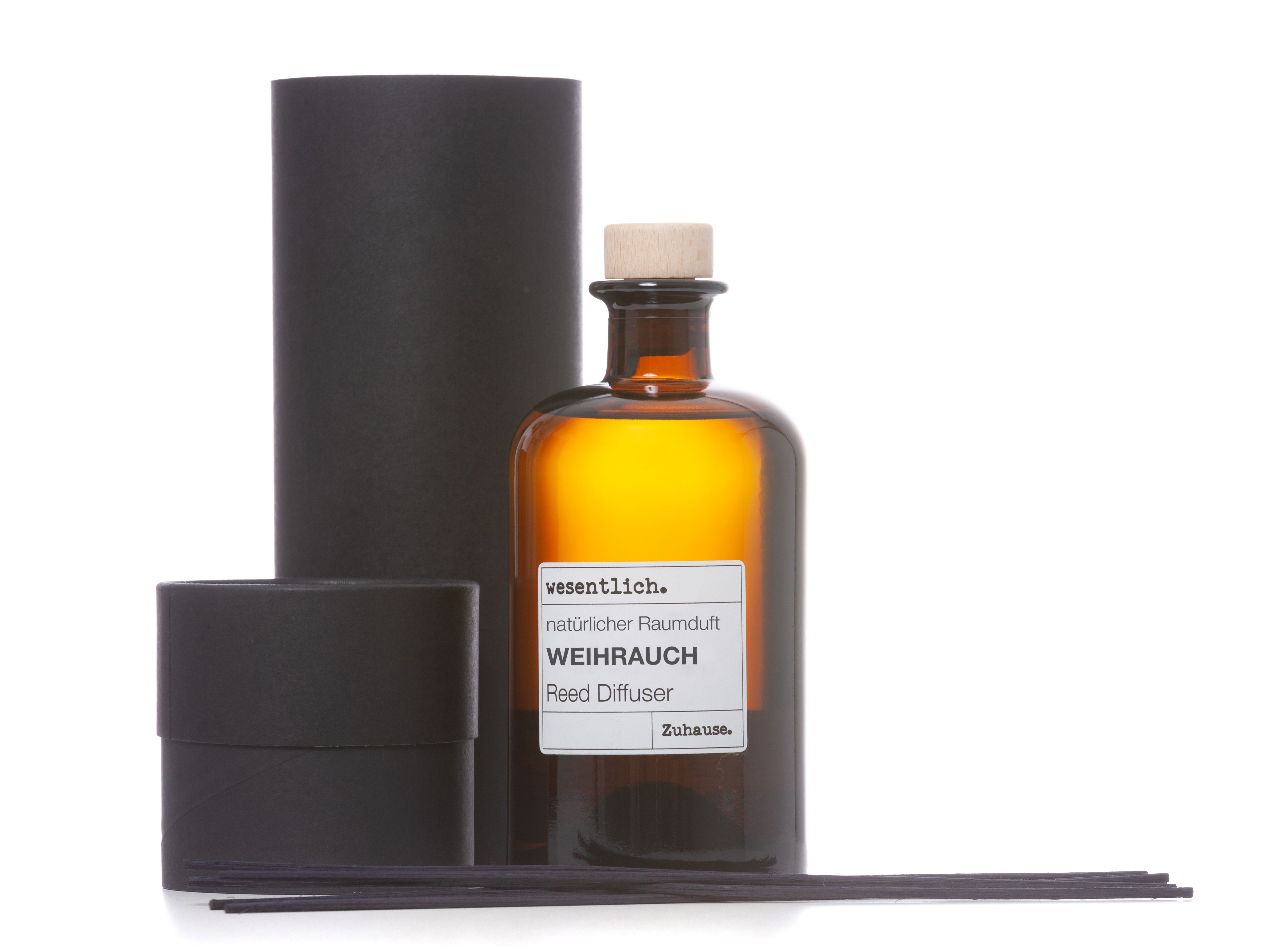 Braune Glasflasche mit Korken, schwarzer Karton, schwarze Stäbchen. Aufschrift: Weihrauch, Reed Diffuser.