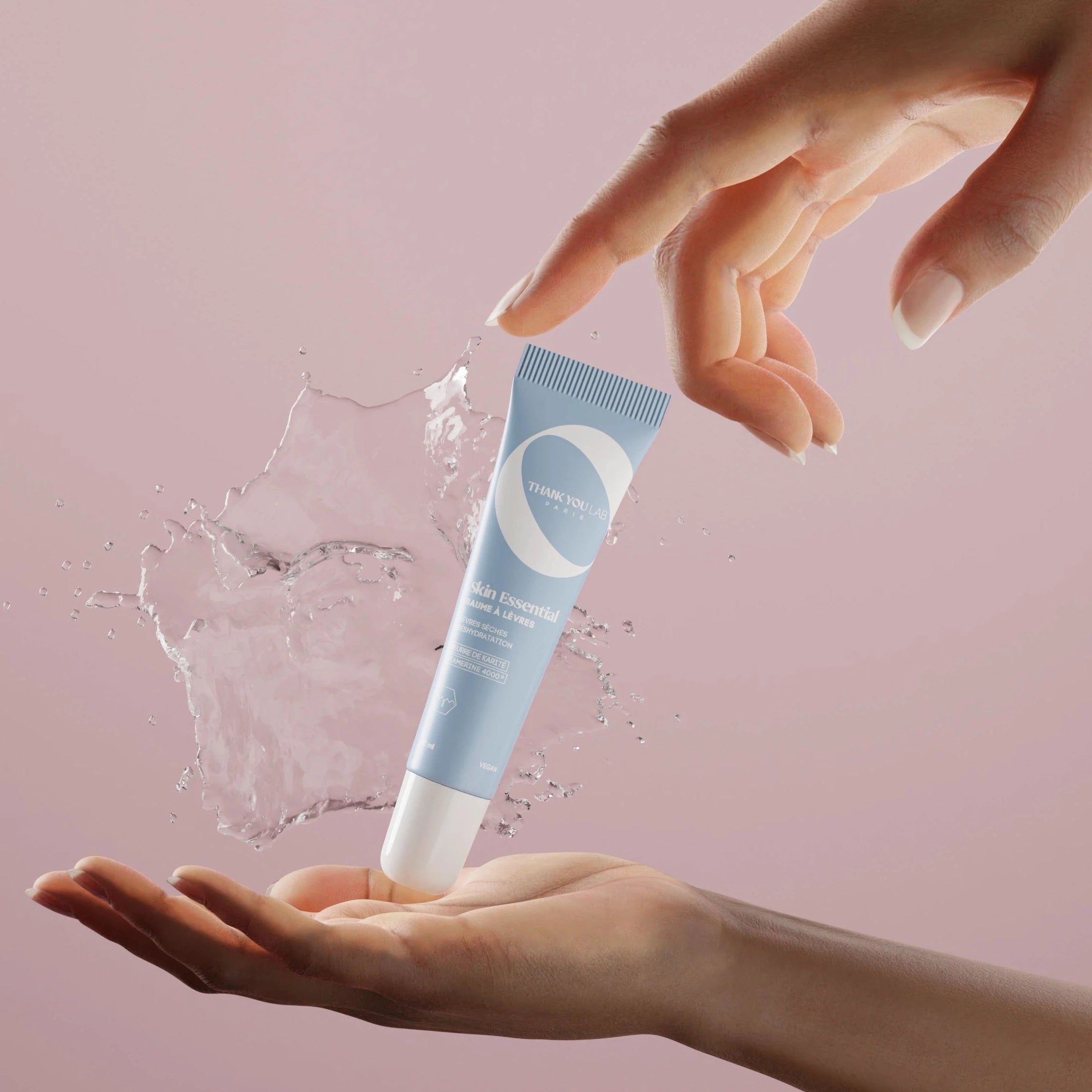 Hellblaues Tubenprodukt, umgeben von Wasserspritzern. Hände halten die Tube und erzeugen den Effekt. Aufschrift sichtbar.