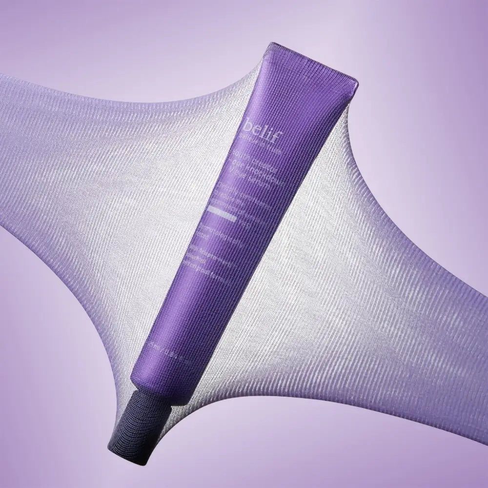 Belif Augencreme-Tube auf lila Stoff. Der Stoff ist dehnbar und transparent.
