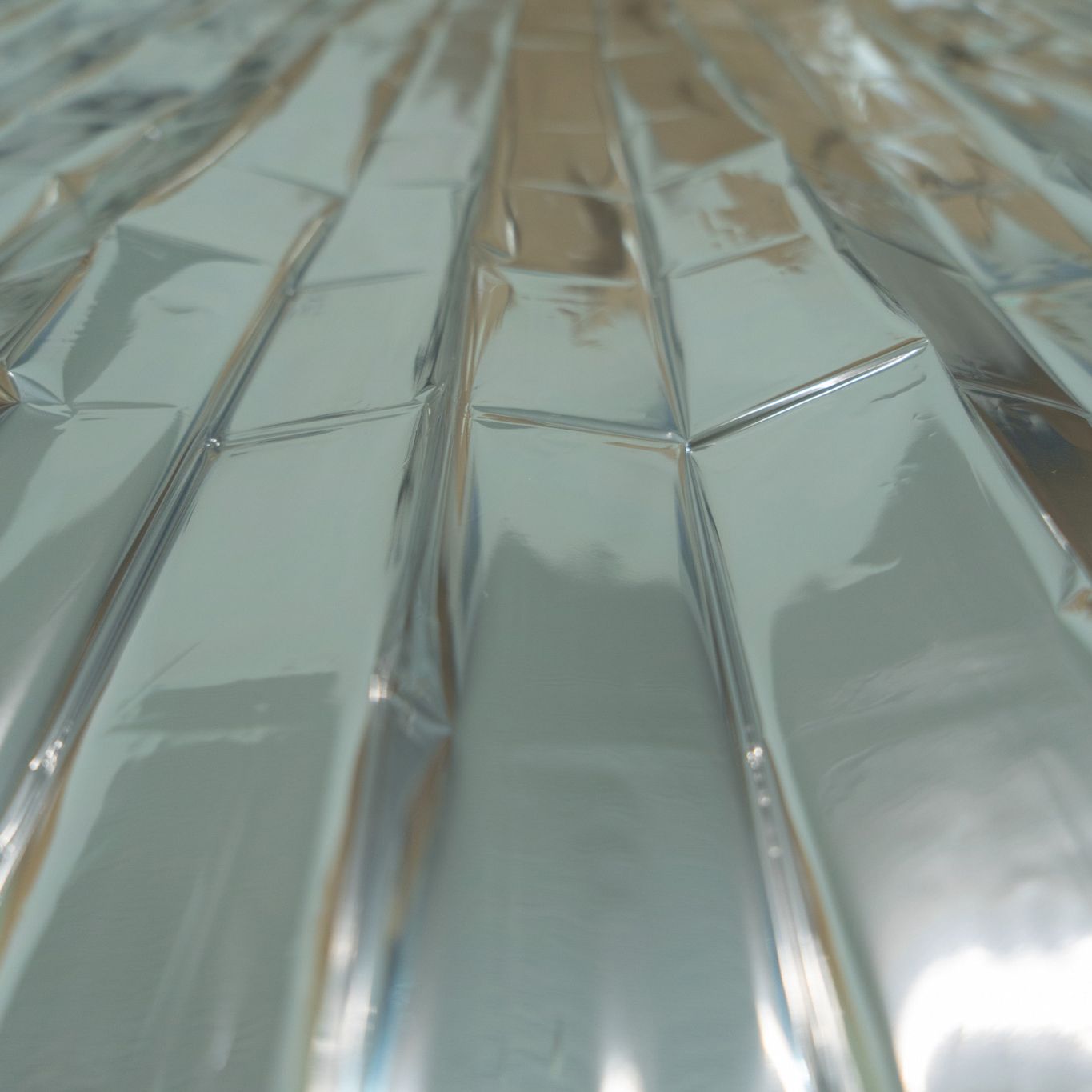 Silberne Innenseite einer Rettungsdecke. Reflektierende Oberfläche, gefaltet.