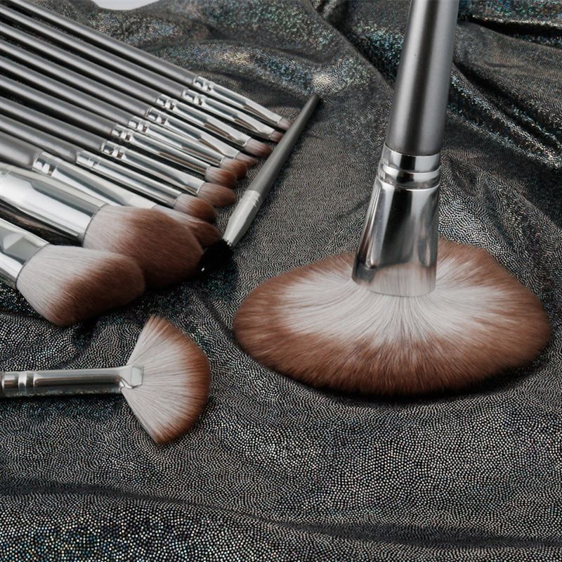 Nahaufnahme eines Make-up-Pinsel-Sets auf glänzendem, silberfarbenem Stoff. Verschiedene Pinselformen.