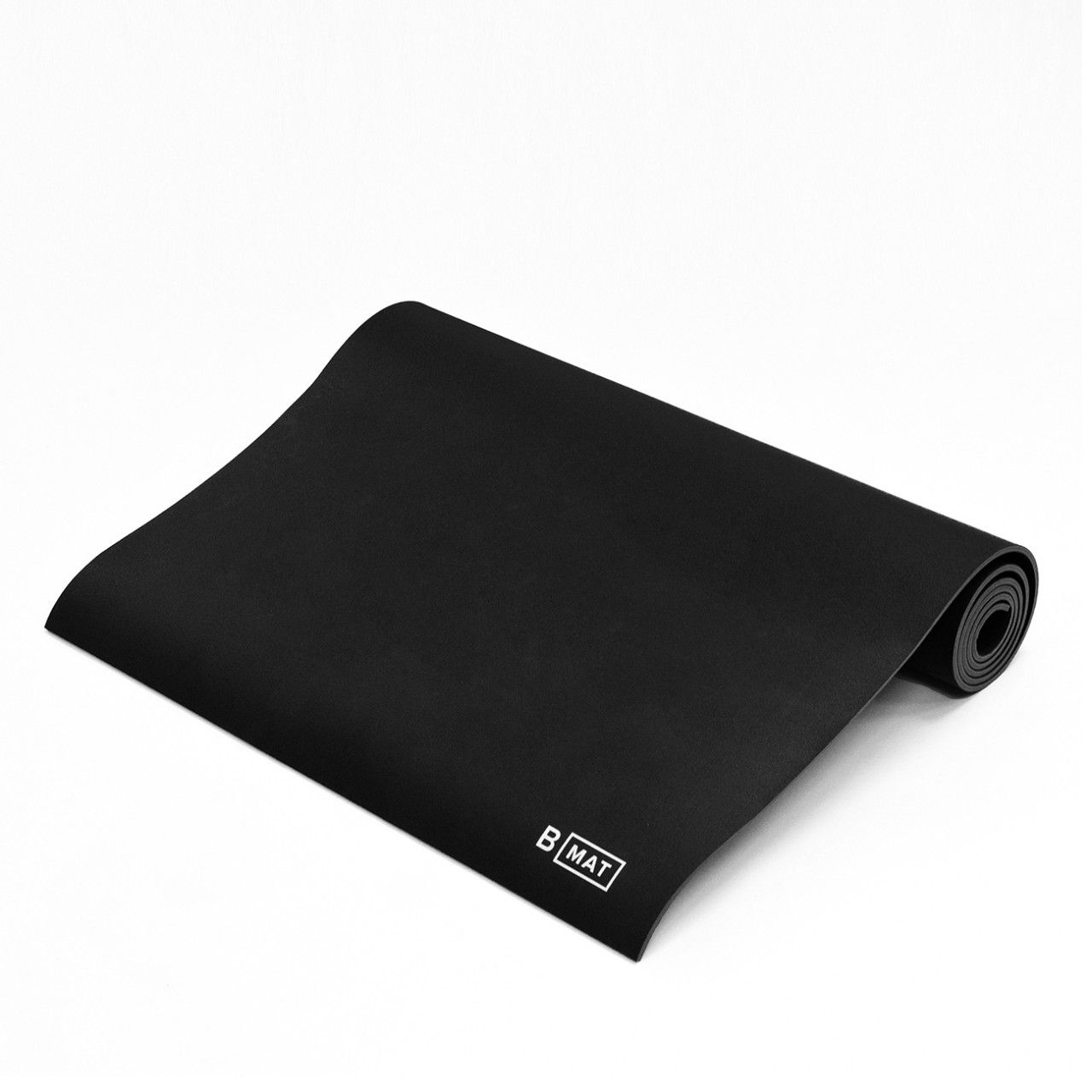 Schwarze Yogamatte, teilweise ausgerollt. Das Logo "B MAT" ist in der Ecke sichtbar.