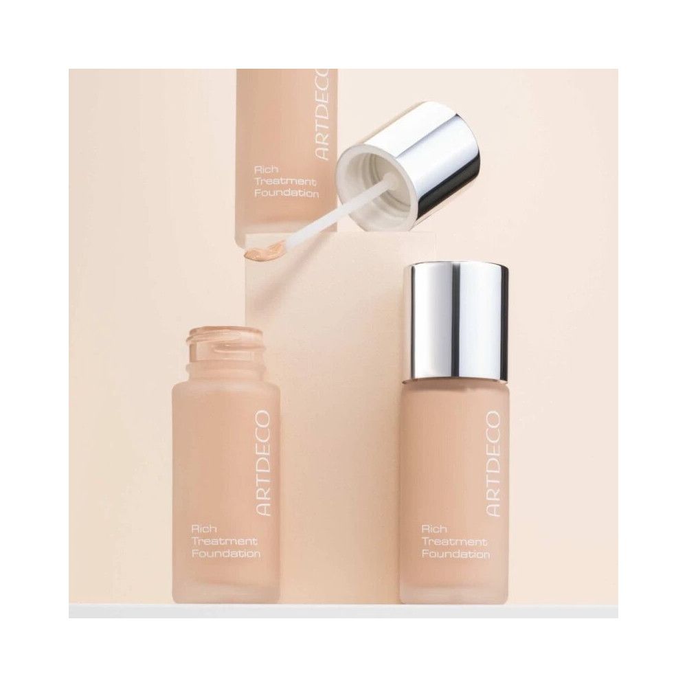 Artdeco Rich Treatment Foundation. Flasche mit silbernem Deckel und Applikator. Produktname und Marke sichtbar.