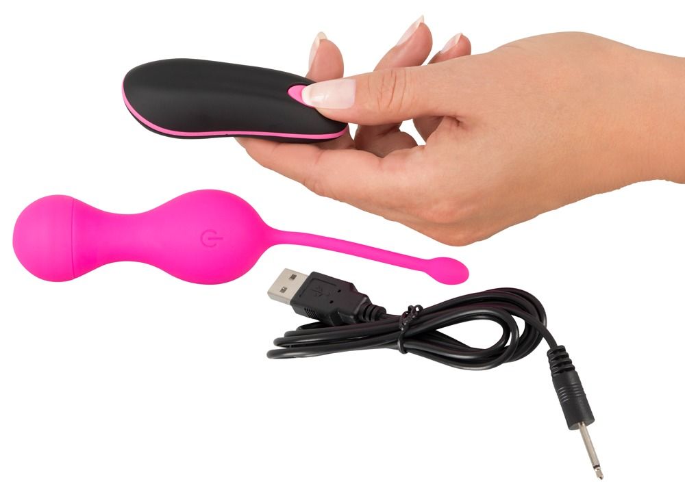 Rosa Duo-Vibrokugel, schwarze Fernbedienung und USB-Kabel. Die Kugel wird von einer Hand gehalten.