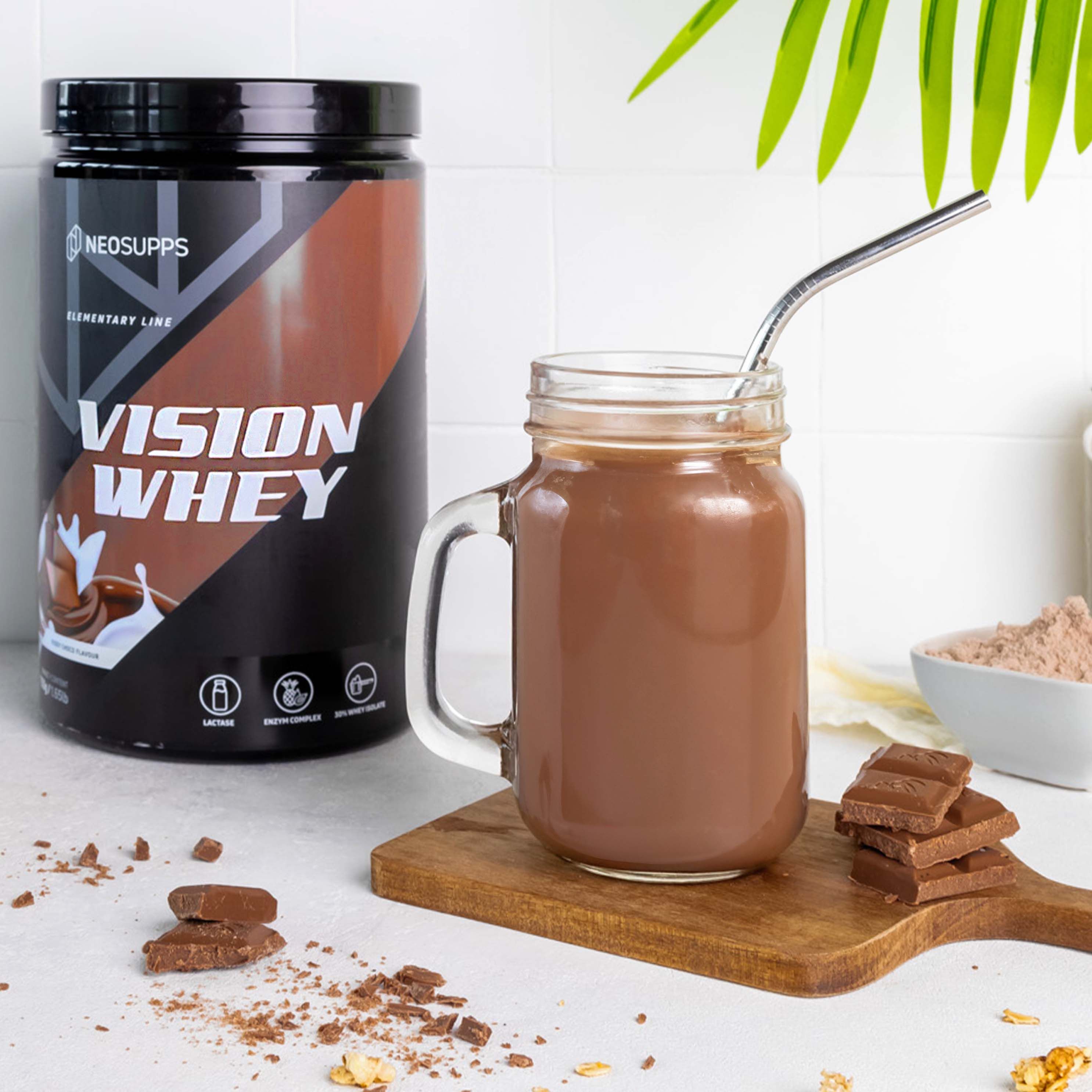 Glas mit Schokoladengetränk, Dose Vision Whey. Aufschrift: Vision Whey, Kiddy Choco. Braune Dose mit schwarzem Deckel. Strohhalm.