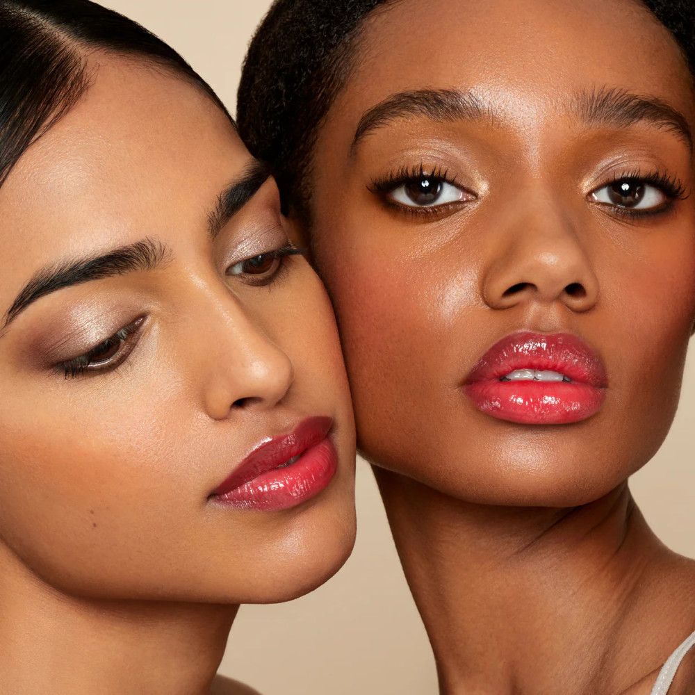 Zwei Frauen mit getönten Lippen. Beide haben glänzende Lippen. Eine Frau hat dunkle Haut, die andere helle Haut.