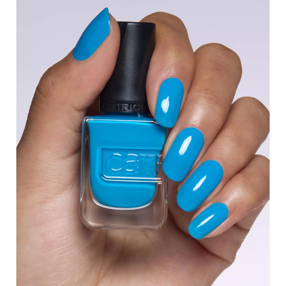 Hand mit lackierten Nägeln und Nagellackflasche. Der Nagellack ist blau. Der Markenname ist auf der Flasche sichtbar.