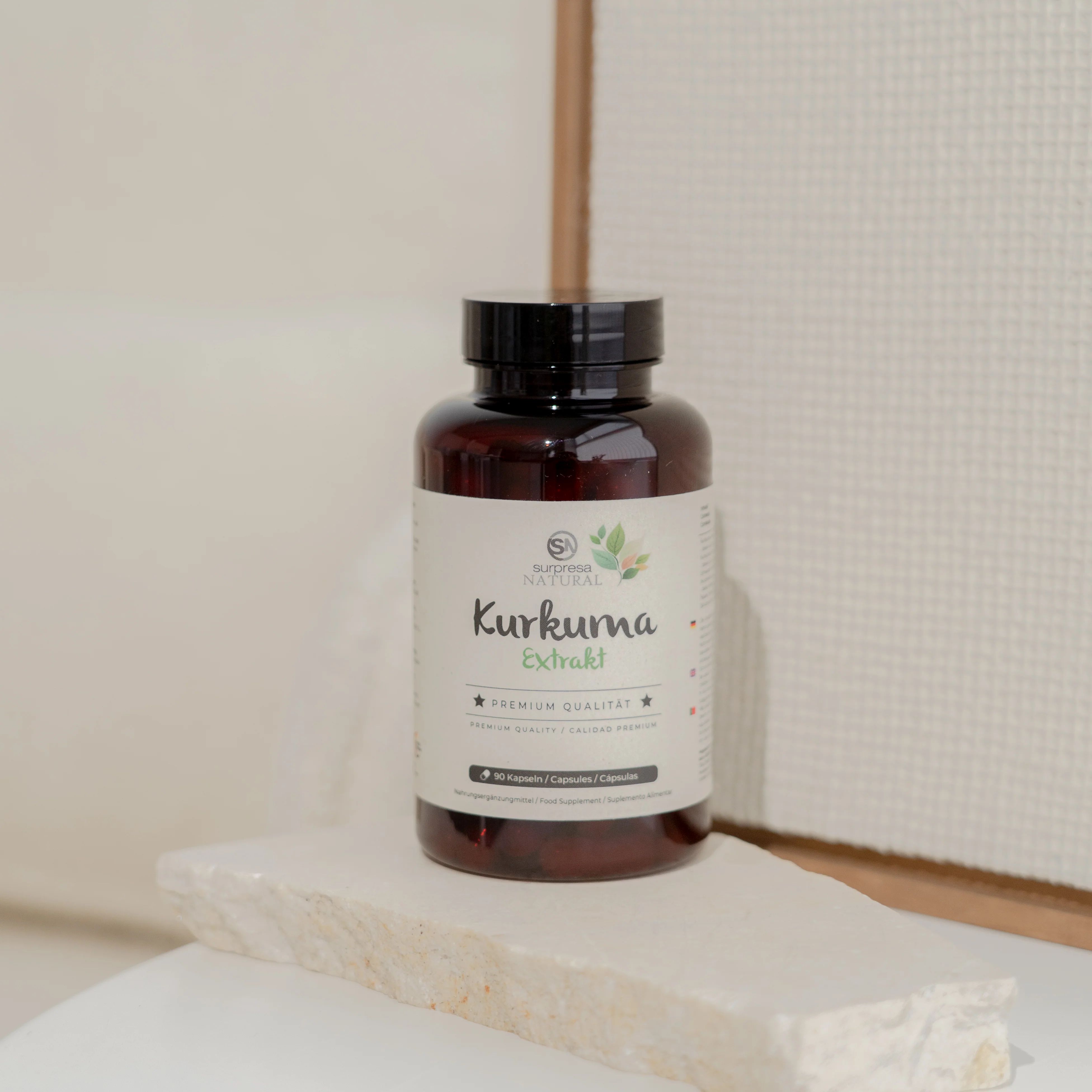 Braune Flasche mit Etikett. Aufschrift: Surpresa Natural Kurkuma Extrakt. Premium Qualität. Steht auf einer hellen Oberfläche.