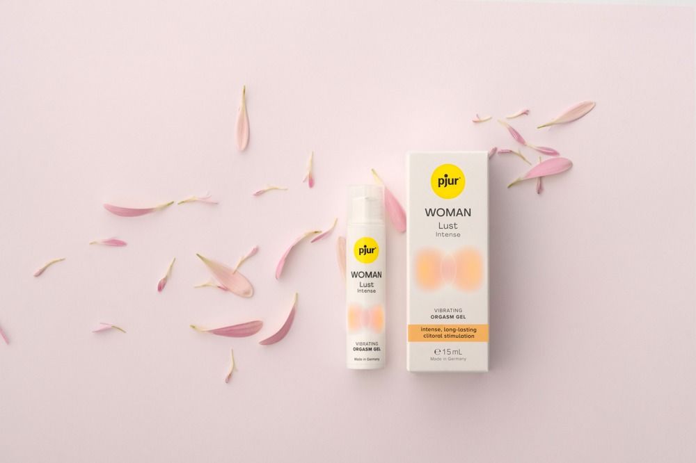 Pjur WOMAN Lust Intense. Gel und Verpackung. Rosa Blütenblätter. Gelb-orangefarbene Grafik. Made in Germany.