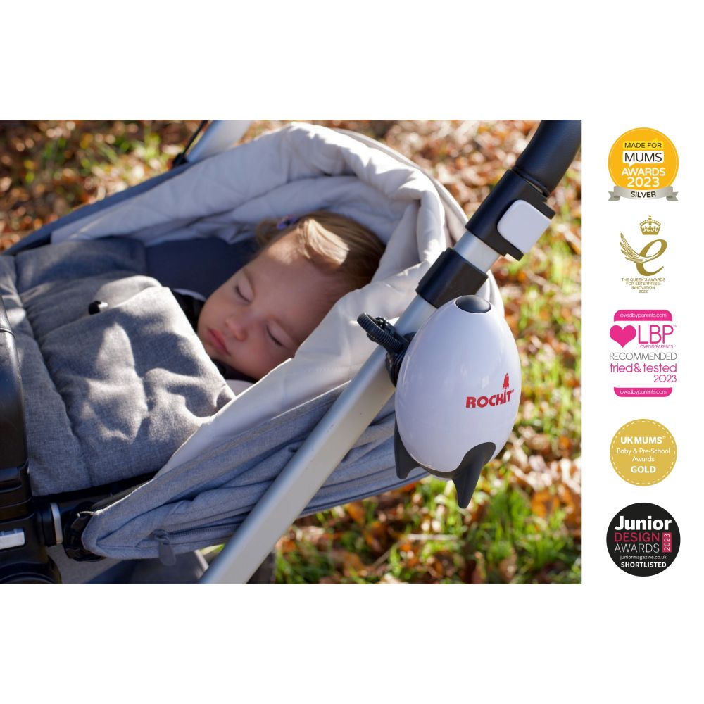 Ein Baby schläft in einem Kinderwagen, an dem ein Rockit Rocker befestigt ist. Der Rockit ist weiß mit schwarzen Elementen. Mehrere Auszeichnungen.