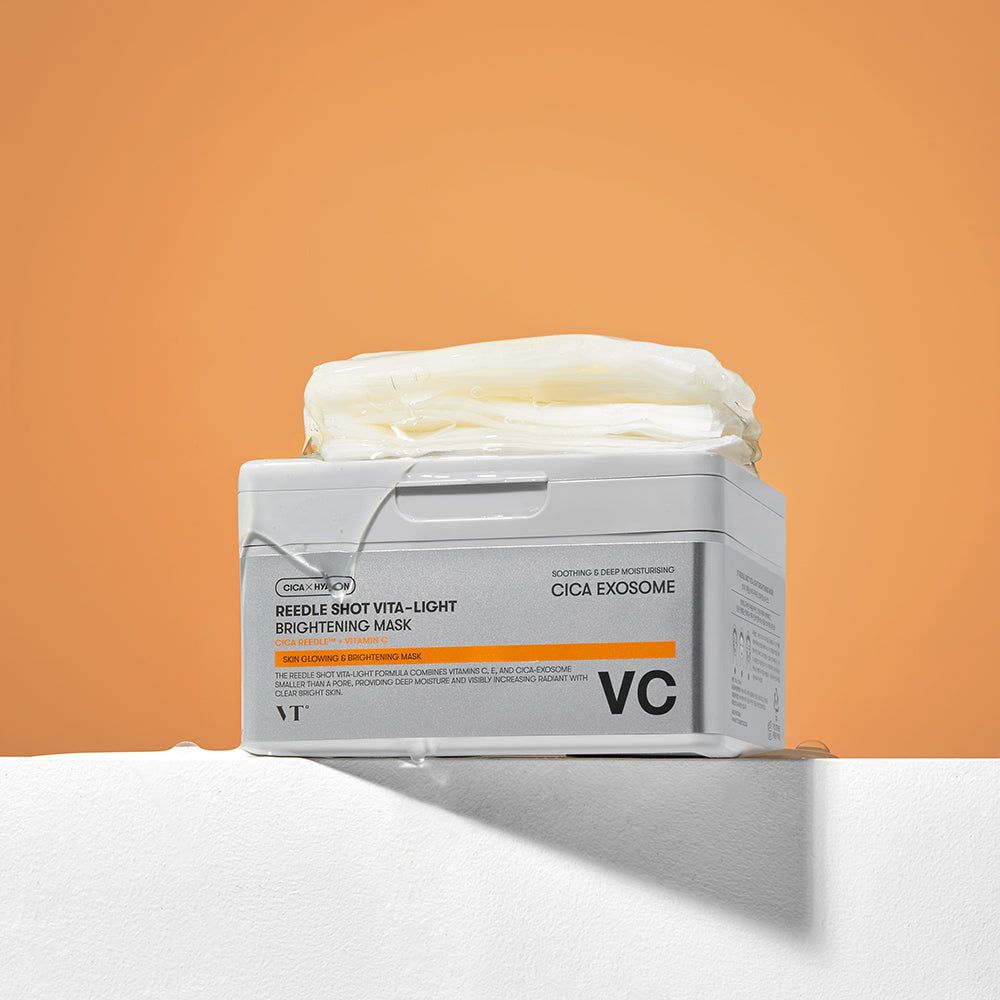 Graue Box mit Masken auf weißem Podest vor orangefarbenem Hintergrund. Aufschrift: Reedle Shot Vita-Light Brightening Mask. Marke: VT.