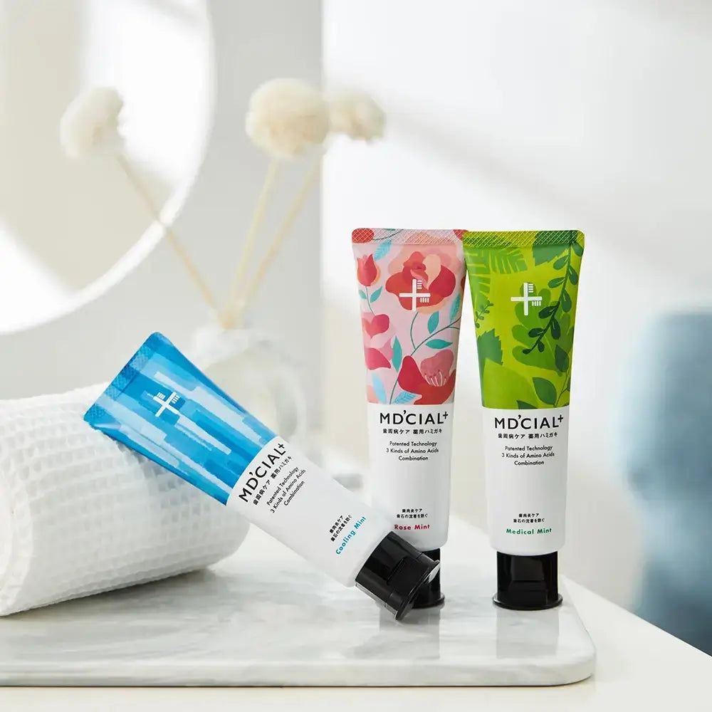 Drei Zahnpasta-Tuben, MD'CIAL+. Rose Mint, Cooling Mint, Medical Mint. Auf weißer Oberfläche.