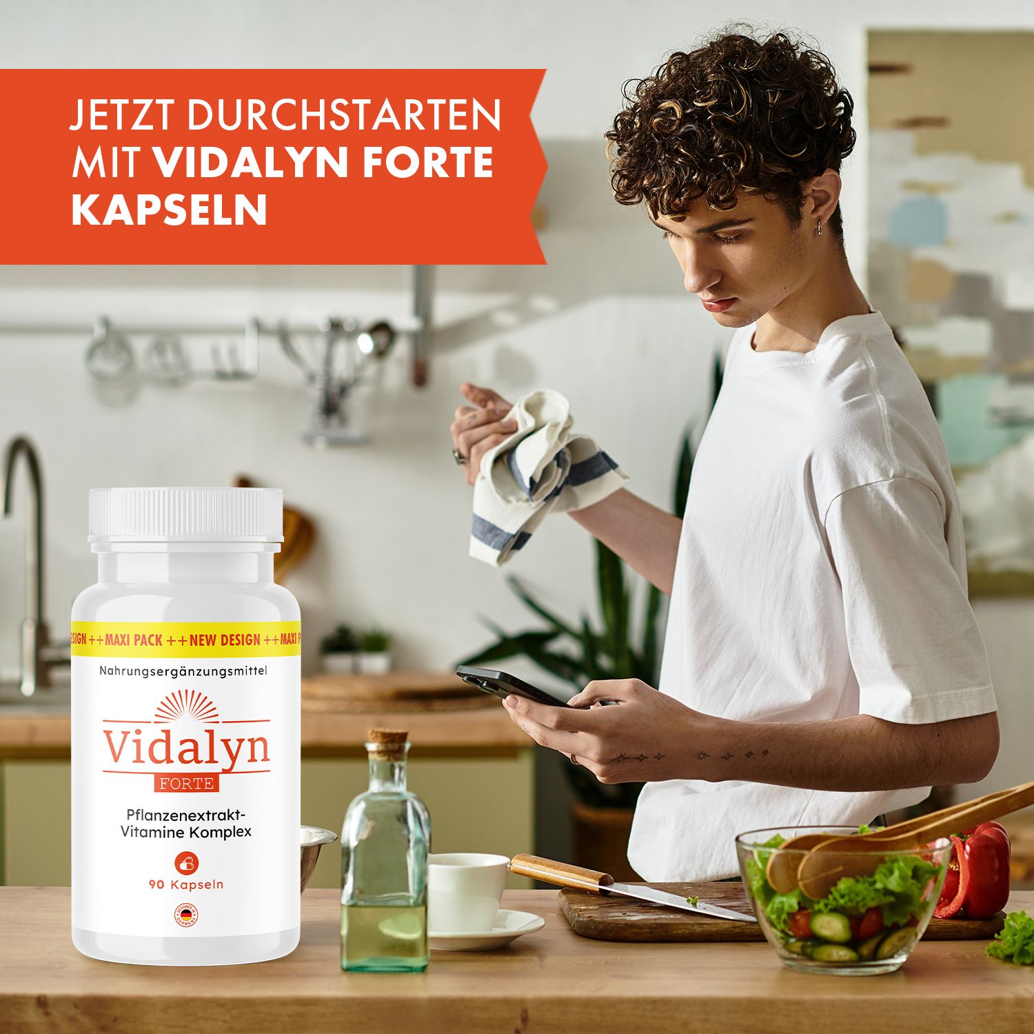 Mann in der Küche mit Vidalyn Forte Kapseln Flasche. Auf dem Tisch: Ölflasche, Tasse, Salat. Text: Jetzt durchstarten mit Vidalyn Forte Kapseln.