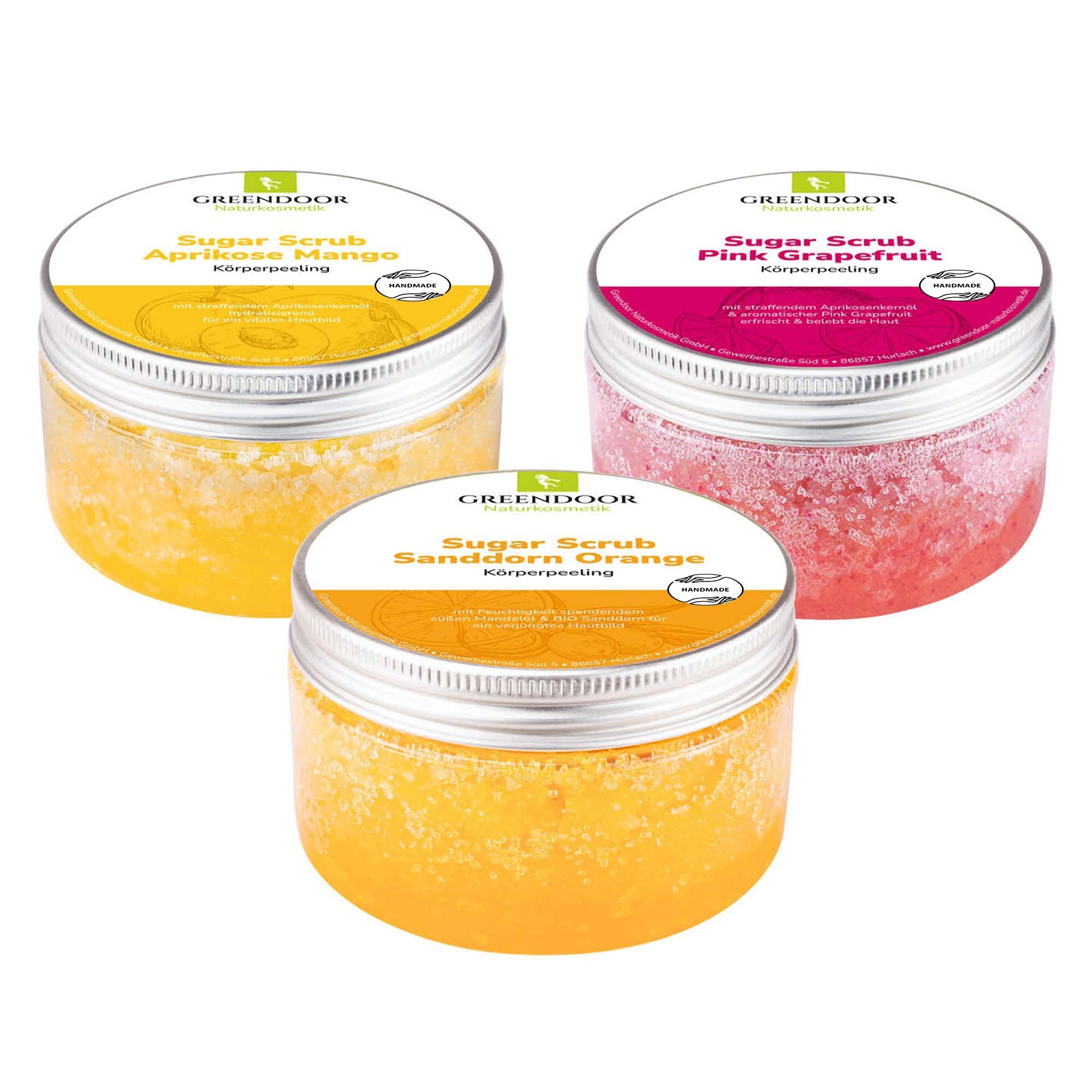 Drei GREENDOOR Körperpeeling Sugar Scrubs in Gelb, Rosa und Orange.