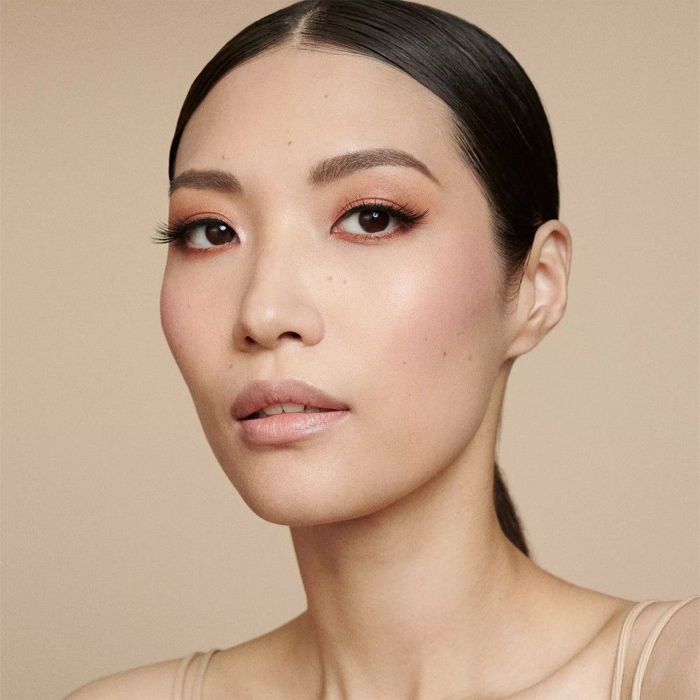 Porträt einer Frau mit Make-up. Geformte Augenbrauen, Lidschatten, Rouge und Lippenstift. Heller Hintergrund.