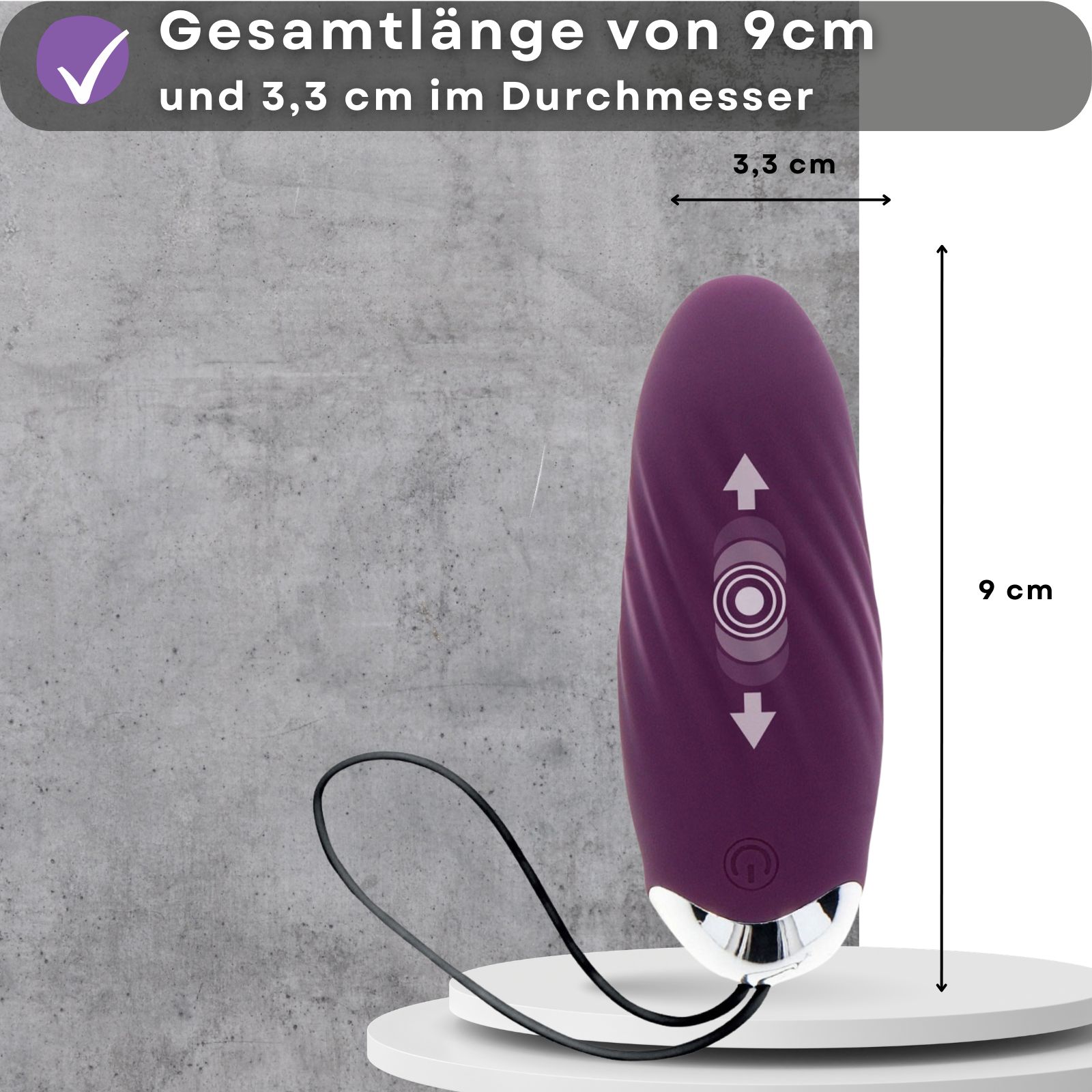Lila Ei-Vibrator. Maße: 9 cm lang, 3,3 cm Durchmesser. Auf Podest. Grauer Hintergrund.