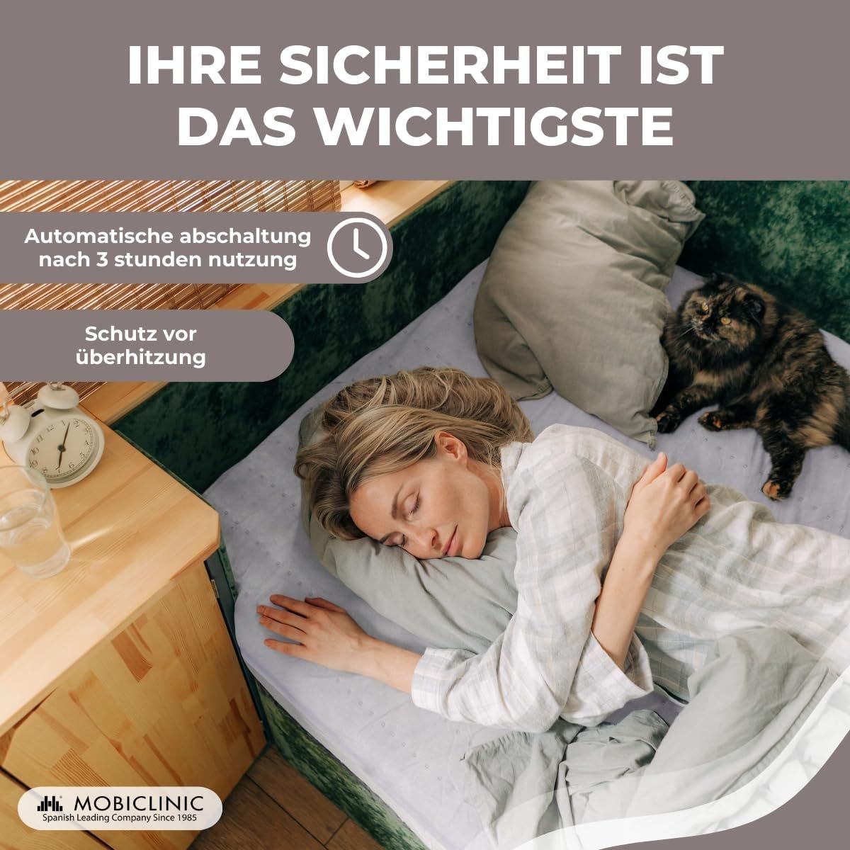 Eine Frau schläft unter einer Decke, eine Katze liegt daneben. Sicherheitshinweise sind aufgedruckt.