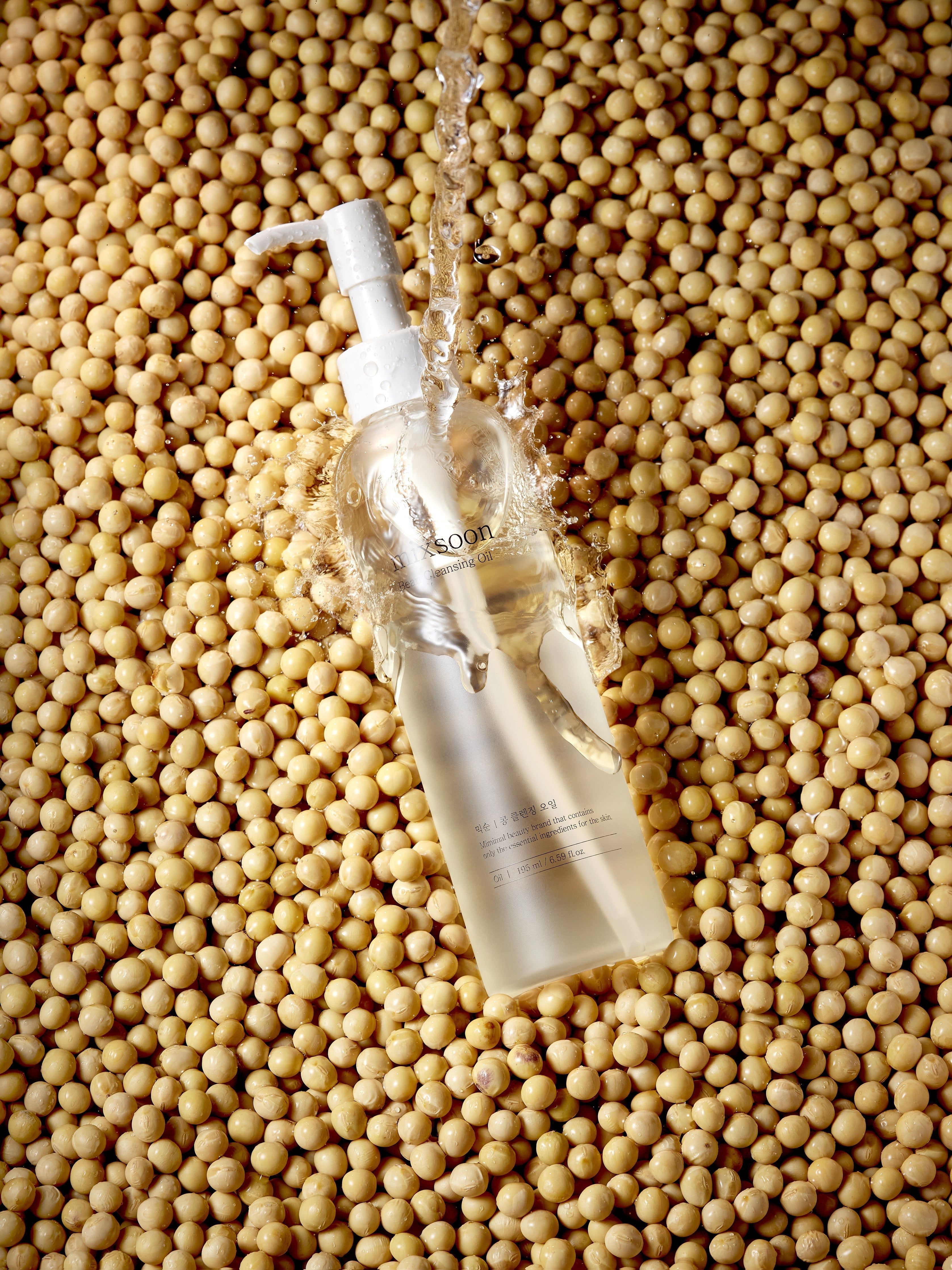 mixsoon Bean Cleansing Oil Flasche inmitten von Sojabohnen, mit Wasser übergossen.