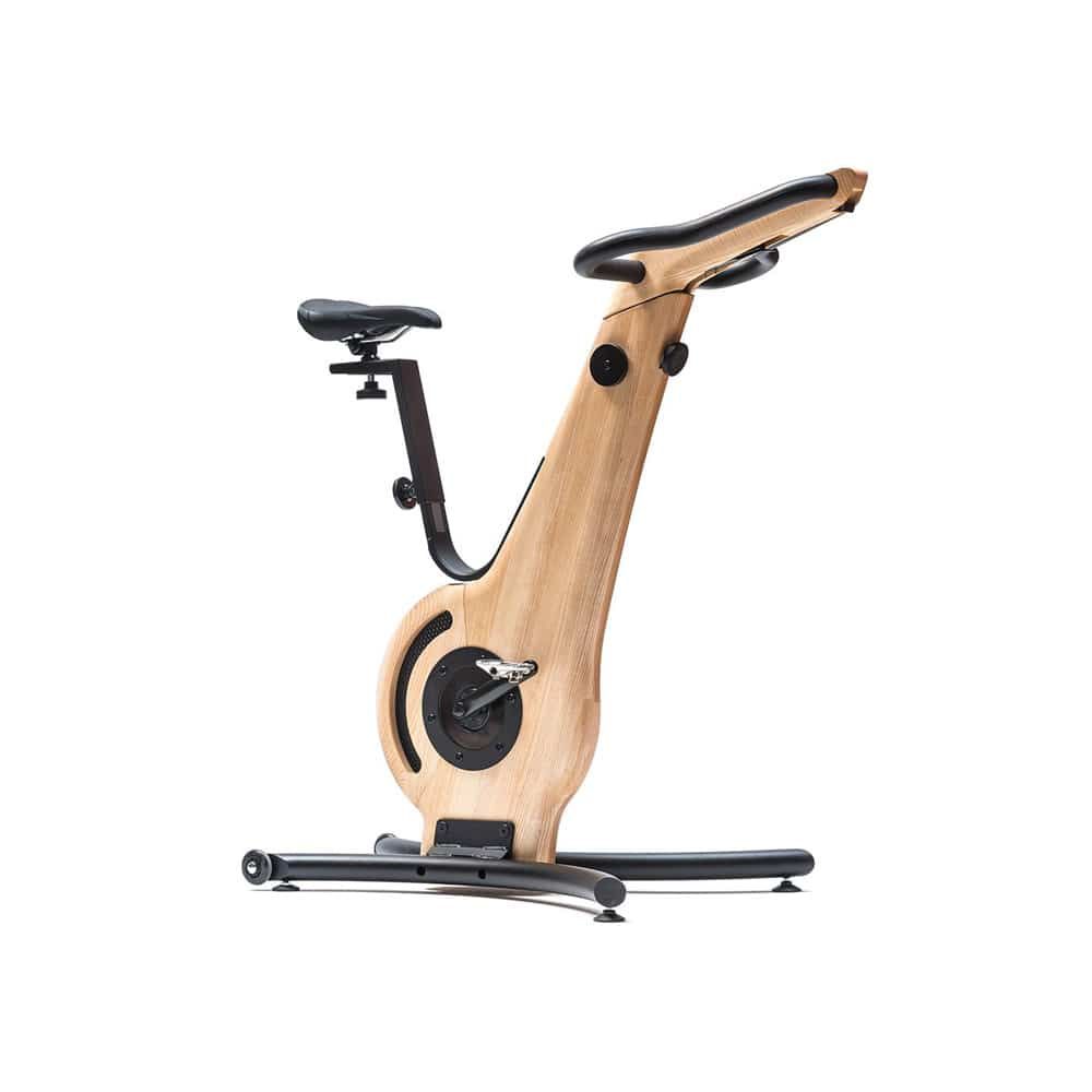 Hometrainer aus Holz. Rahmen, Lenker und Sattelstütze aus hellem Holz. Schwarzer Sattel und Lenkergriffe. Schwarze Pedale und Standfuß.