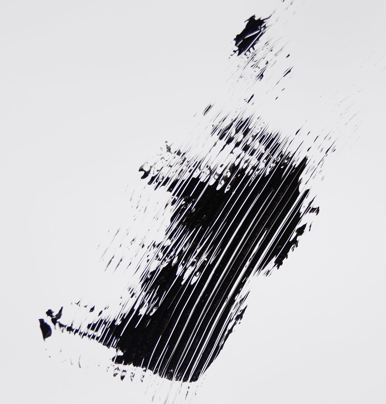 Schwarze Mascara-Bürstenstriche auf weißem Hintergrund. Textur und Farbe des Produkts werden gezeigt.