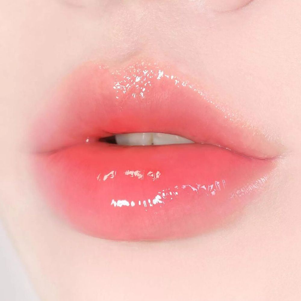 Nahaufnahme von Lippen mit glänzendem, rosa Lippenstift. Die Lippen sind leicht geöffnet.