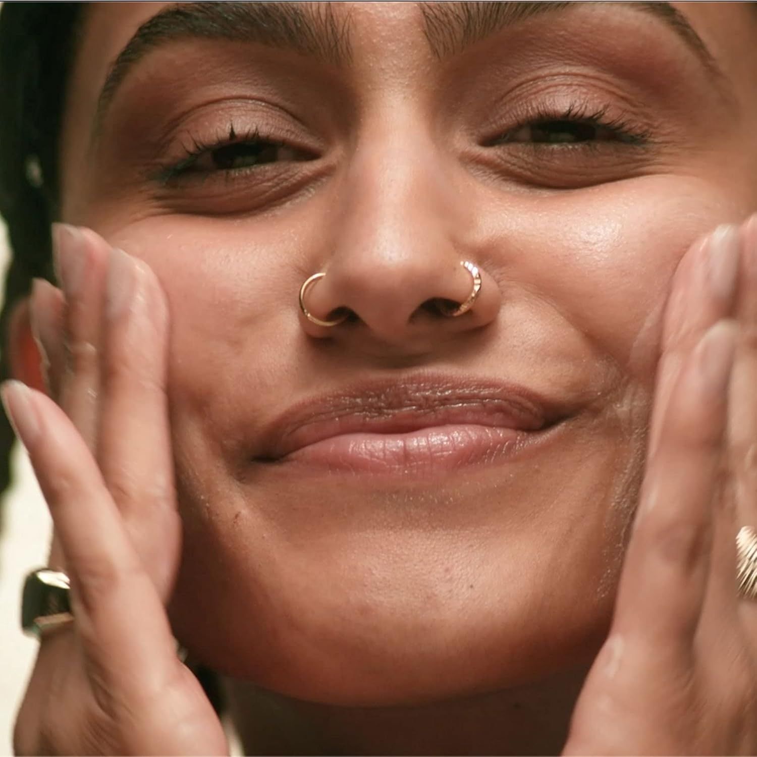 Nahaufnahme einer Person, die ihre Hände auf ihr Gesicht legt. Keine Produkte sichtbar.