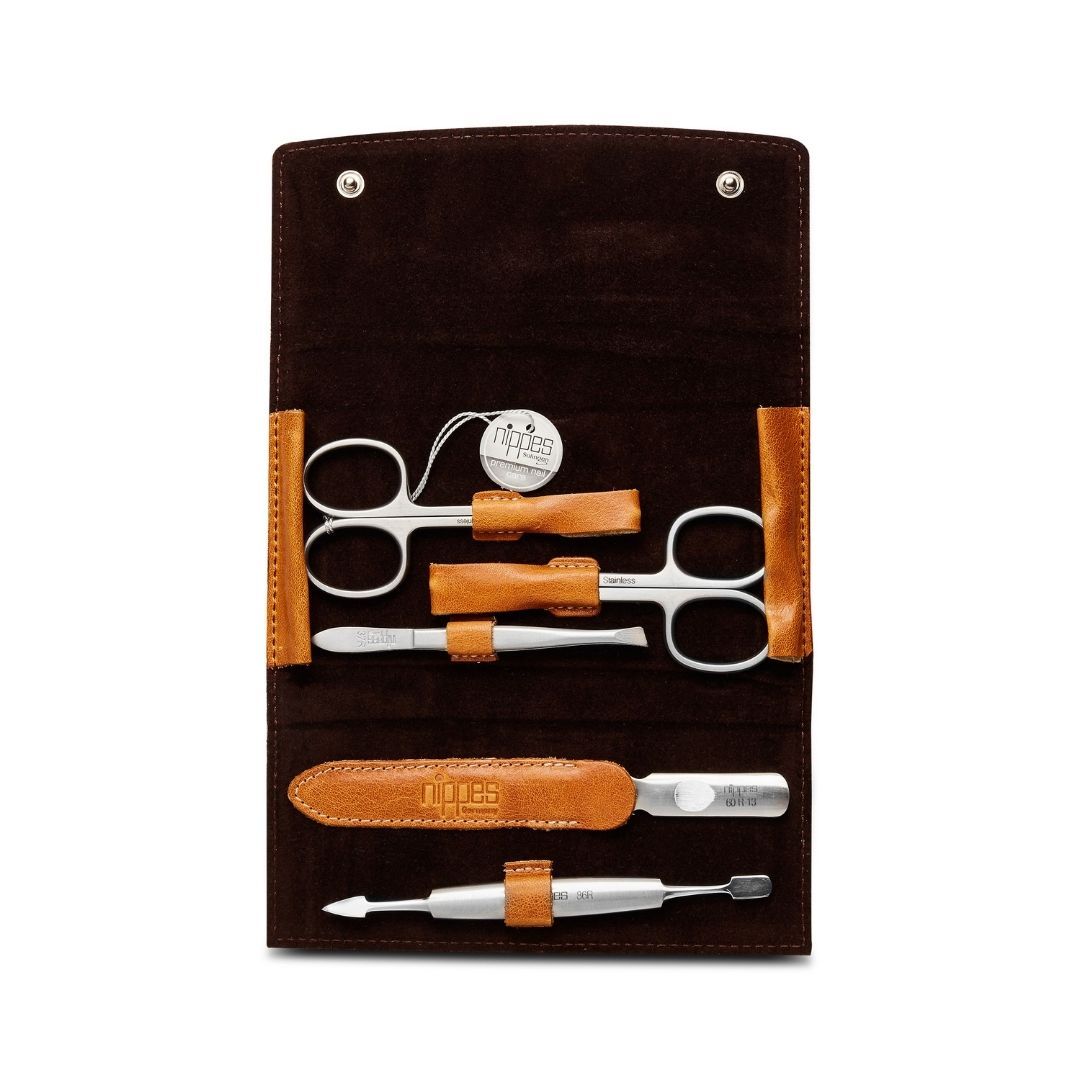 Maniküre-Etui COGNAC, geöffnet. Enthält Schere, Nagelfeile und weitere Instrumente. Braunes Lederetui mit cognacfarbenen Details.