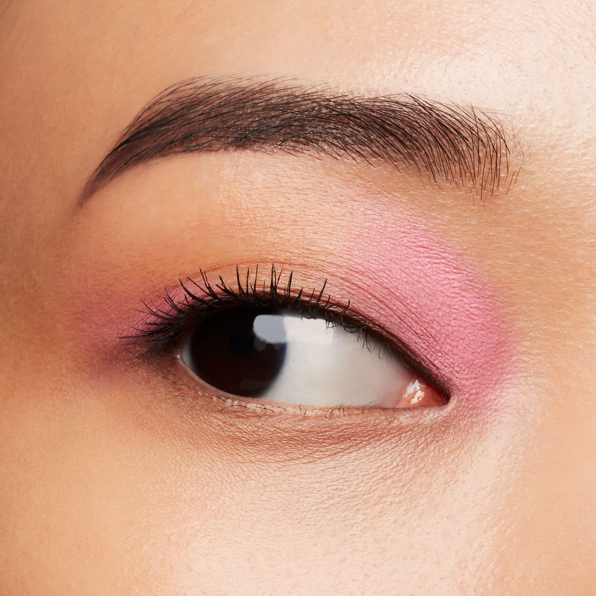 Auge mit rosa Lidschatten. Braune Augenbraue, Wimpern. Blick zur Seite.