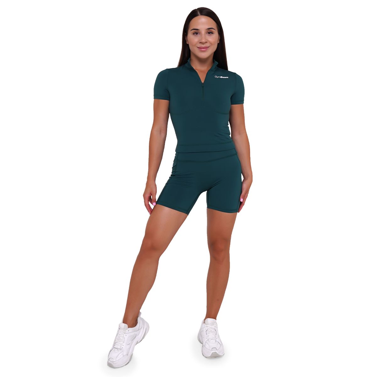 Ganzkörperansicht einer Frau in einem dunkelgrünen Damen-Cropped-Shirt und passenden Shorts.
