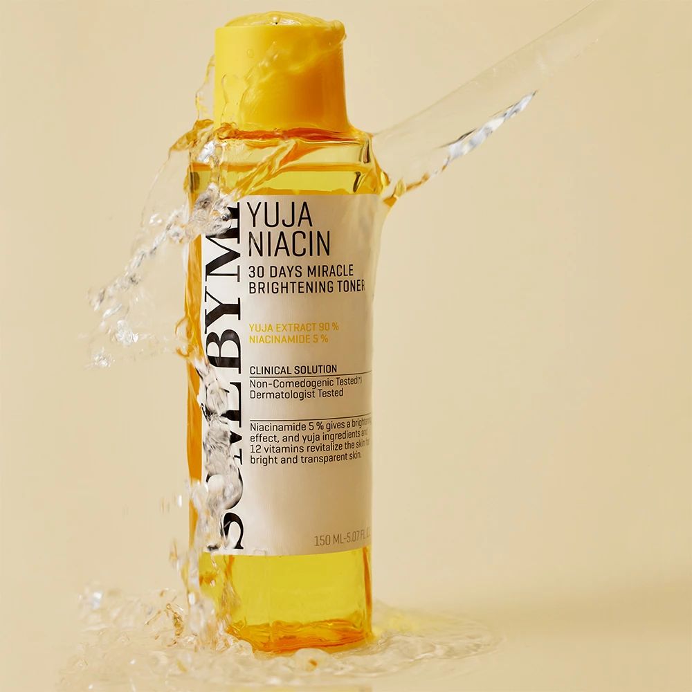 Gelbe Flasche mit gelbem Deckel, umgeben von Wasserspritzern. Aufschrift: Yuja Niacin 30 Days Miracle Brightening Toner.