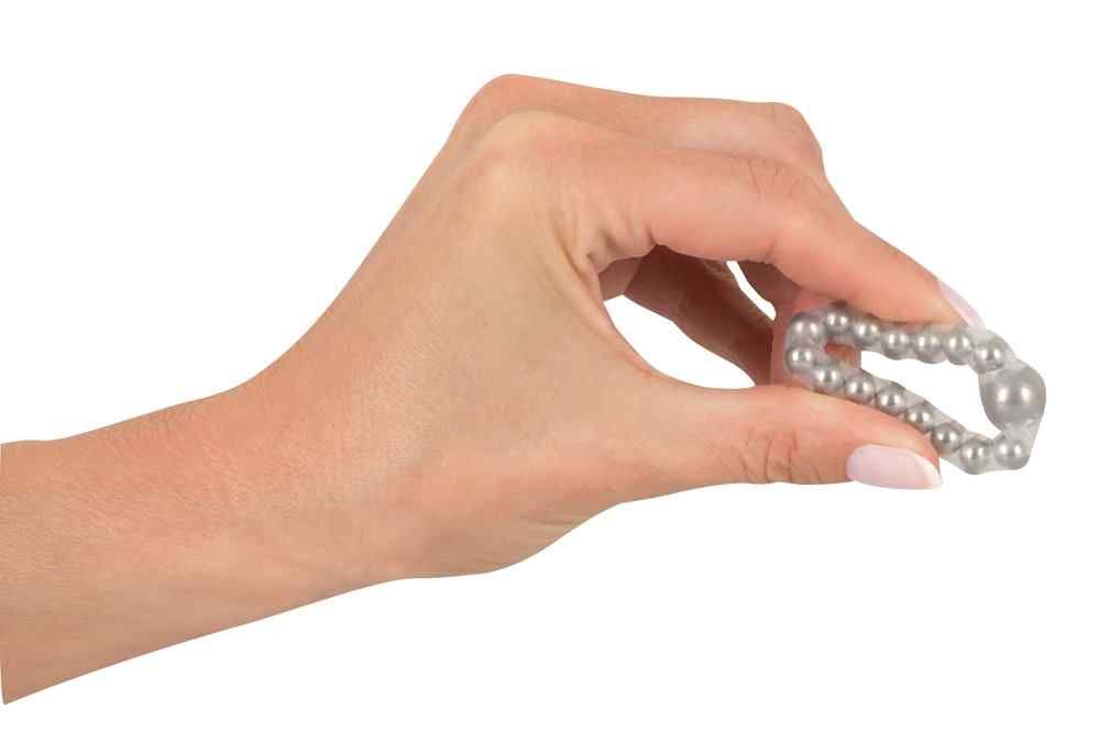 Maximum Metal Ring, in Hand gehalten. Ring mit Perlen. Flexible, transparente Silikonbasis. Metallperlen.