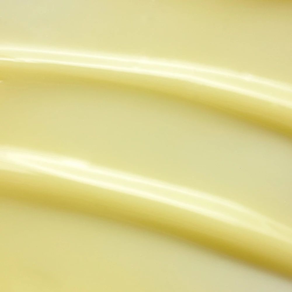 Nahaufnahme von gelber Creme. Zwei wellenförmige Streifen. Keine Beschriftung sichtbar.