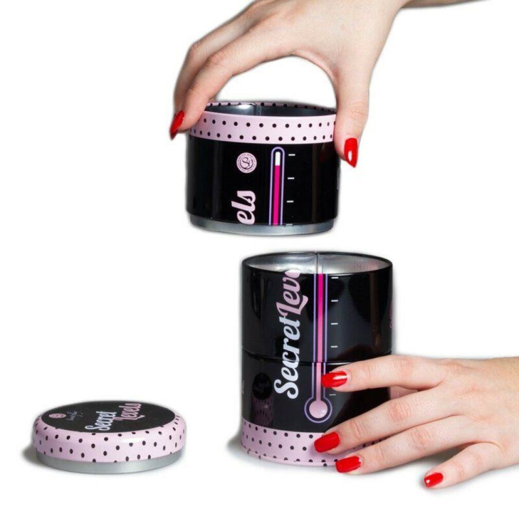 Schwarze Dose mit rosa Punkten und Schriftzug "Secret Levels". Rosa Thermometer-Design. Deckel abgenommen. Hände mit roten Nägeln.