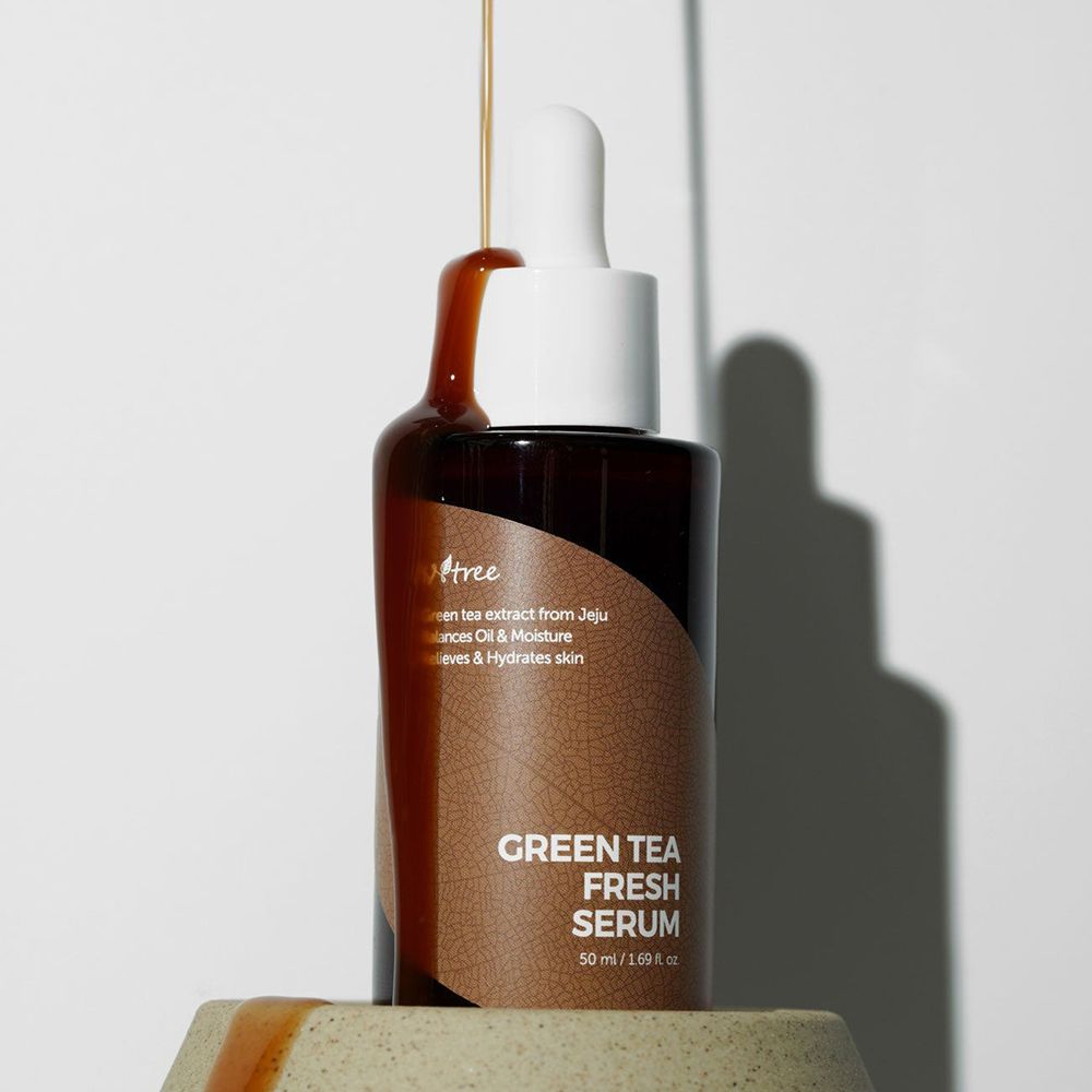 Serum tropft aus einer Flasche. Braune Glasflasche mit weißem Deckel. ISNTREE Green Tea Fresh Serum.