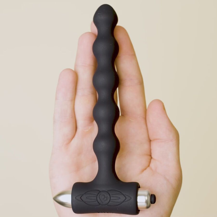 Schwarzer, geriffelter Analplug mit metallischem Ende und Griff. Liegt in einer Hand. Auf dem Griff ist ein Logo zu sehen.