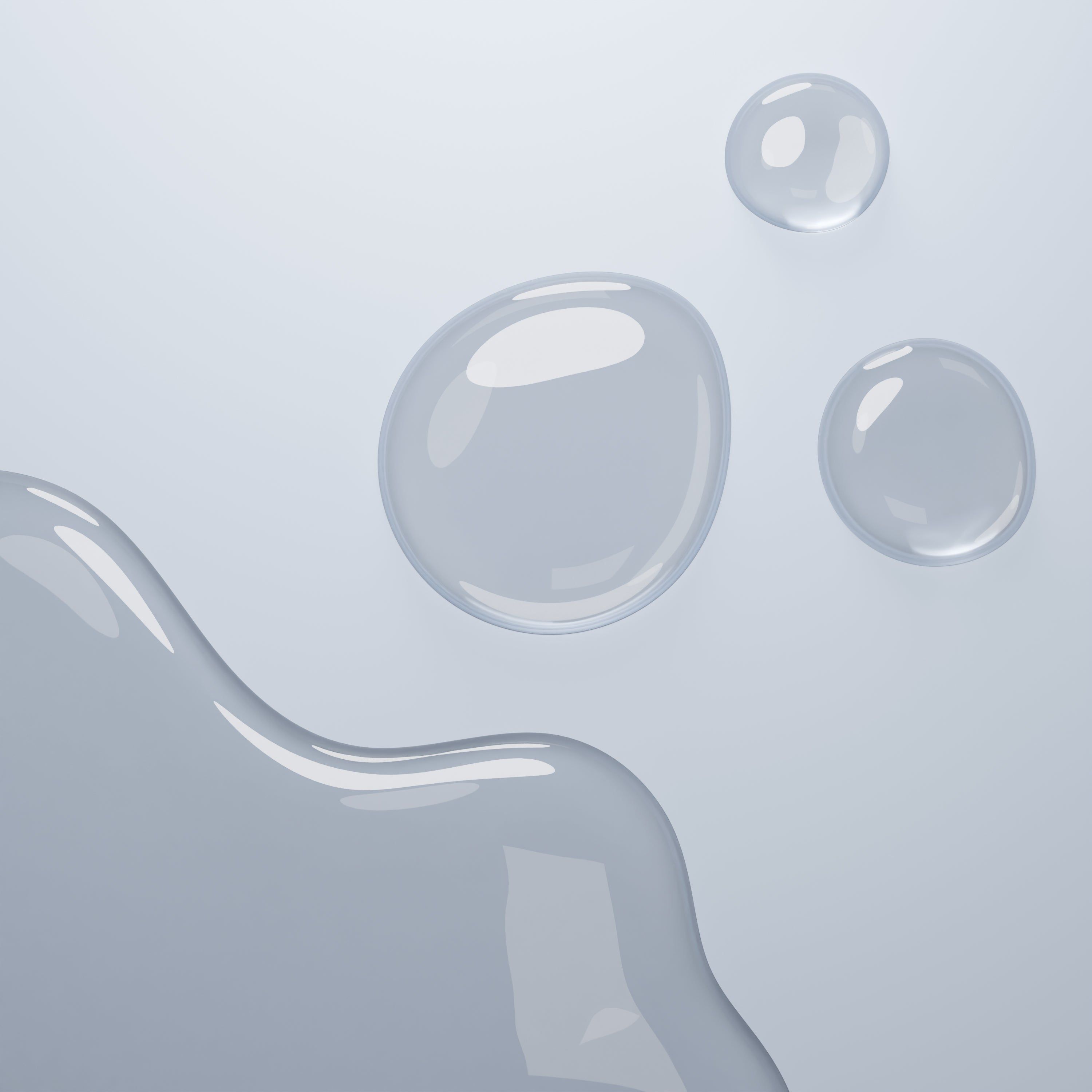 Drei Tropfen einer transparenten Flüssigkeit auf einer hellgrauen Oberfläche. Einige Tropfen sind miteinander verbunden.