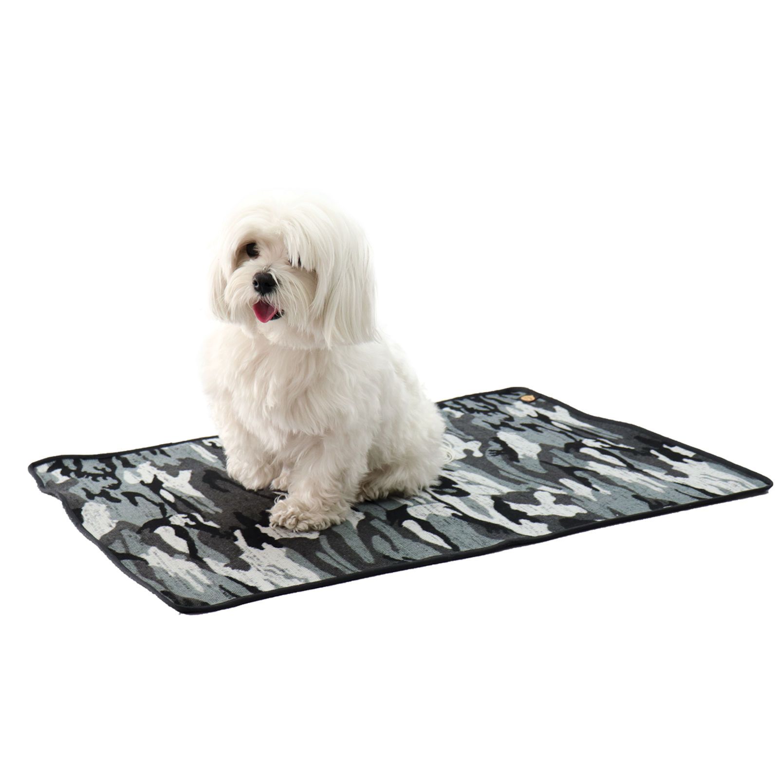 Grau-schwarze Tarnmuster-Decke. Ein kleiner, weißer Hund sitzt darauf.