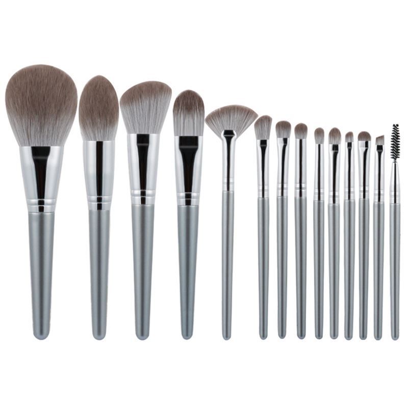 Set aus Make-up-Pinseln mit silberfarbenen Griffen und verschiedenen Pinselköpfen. Aufgereiht auf weißem Hintergrund.
