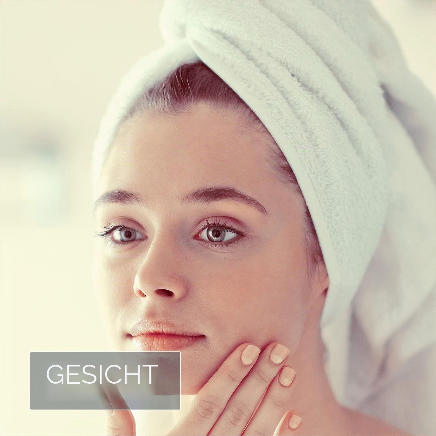 Junge Frau mit Handtuch auf dem Kopf, berührt ihr Gesicht.