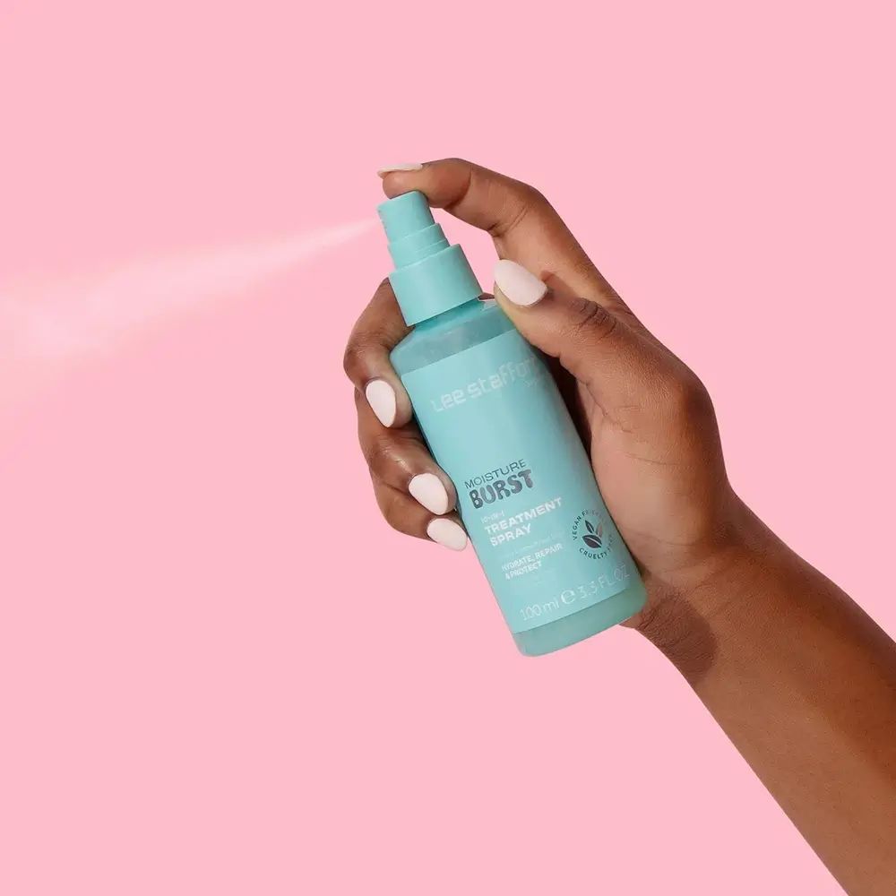 Türkisgrüne Sprühflasche in einer Hand. Sprühnebel sichtbar. Aufschrift: Moisture Burst.