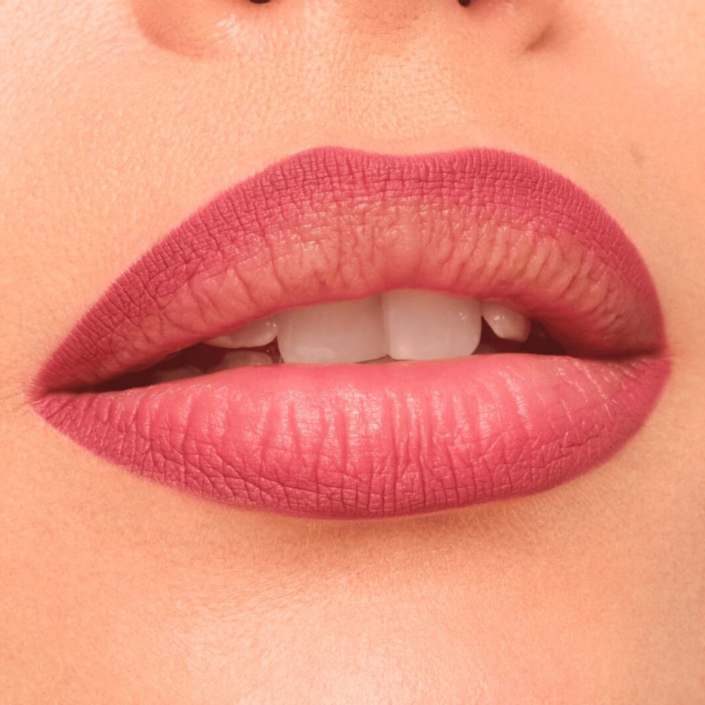 Nahaufnahme von Lippen, die mit einem roten Lippenstift geschminkt sind. Die Lippen sind geöffnet und zeigen Zähne.