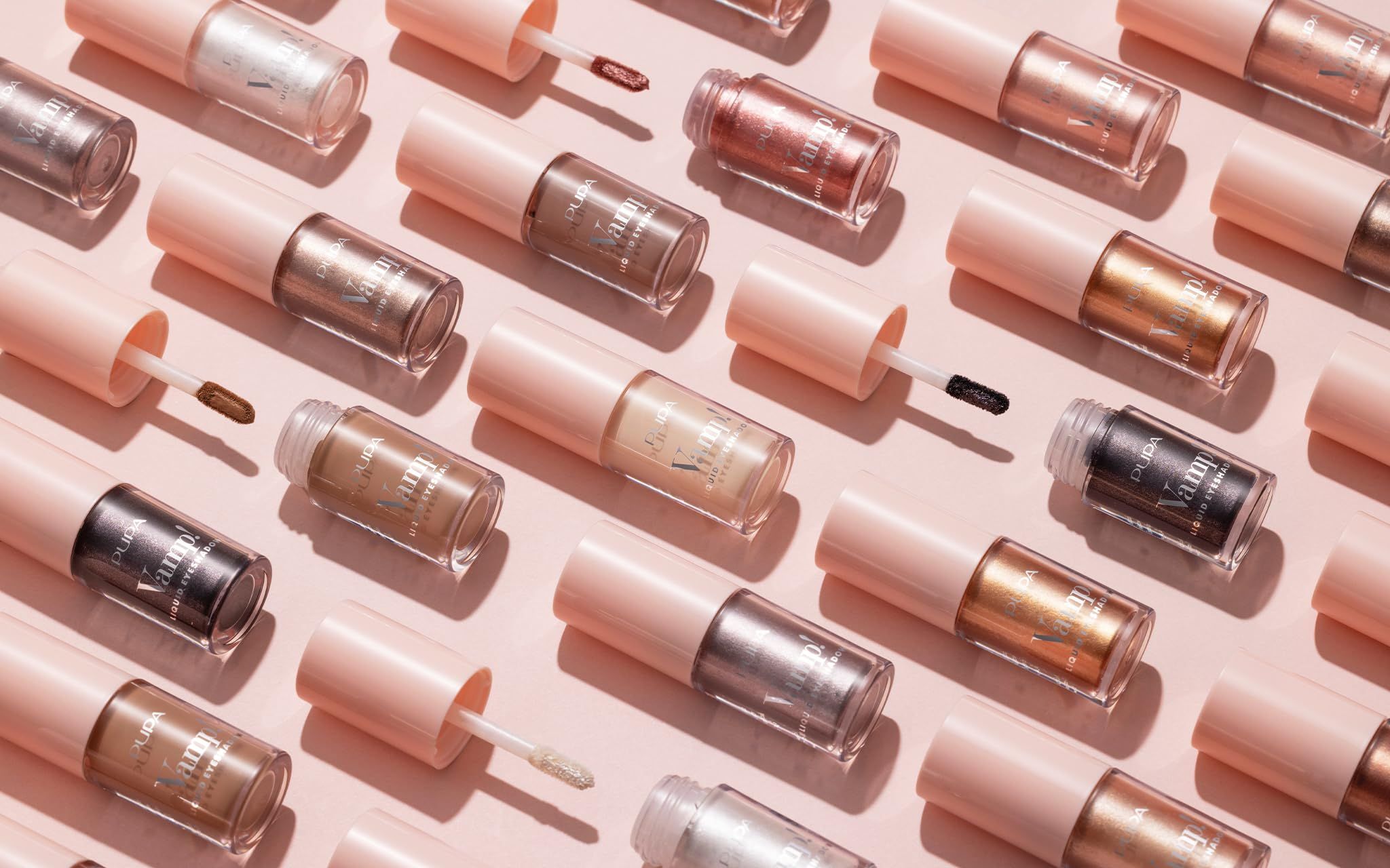 Mehrere Pupa Milano Vamp! Liquid Eyeshadow Flaschen mit rosa Deckeln. Verschiedene Farben. Applikatoren sichtbar.