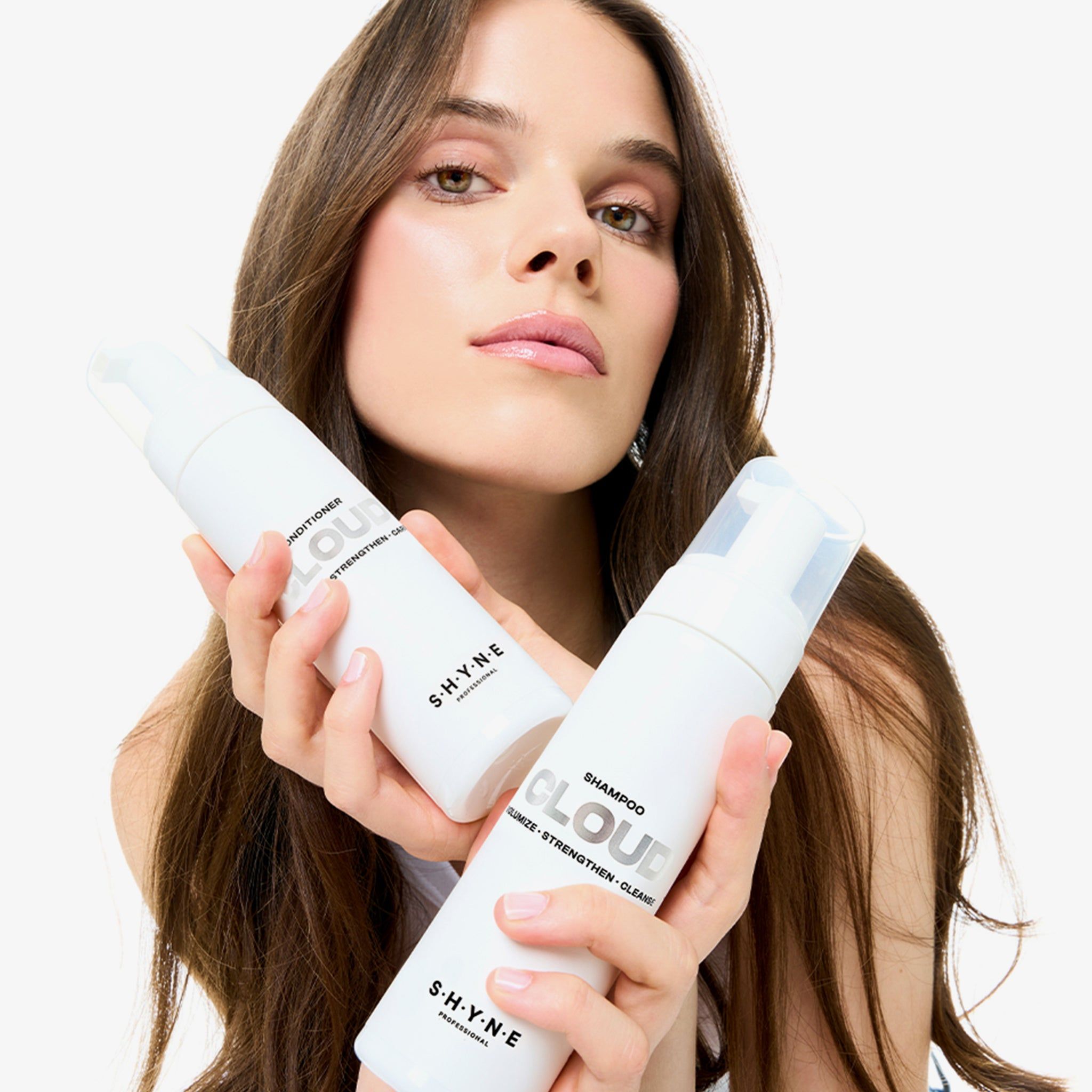 Frau hält zwei weiße Flaschen: SHYNE Cloud Conditioner und Shampoo. Beide mit Sprühkopf.