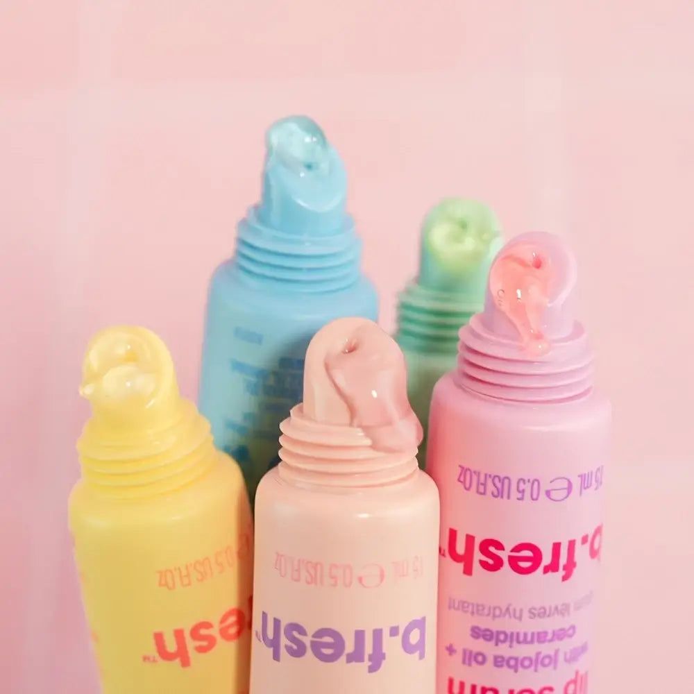 Fünf Tuben Lippen-Serum. Farben: Gelb, Rosa, Hellblau, Grün, Rosa. Marke: b.fresh. Produkt ist aus der Tube herausgedrückt.