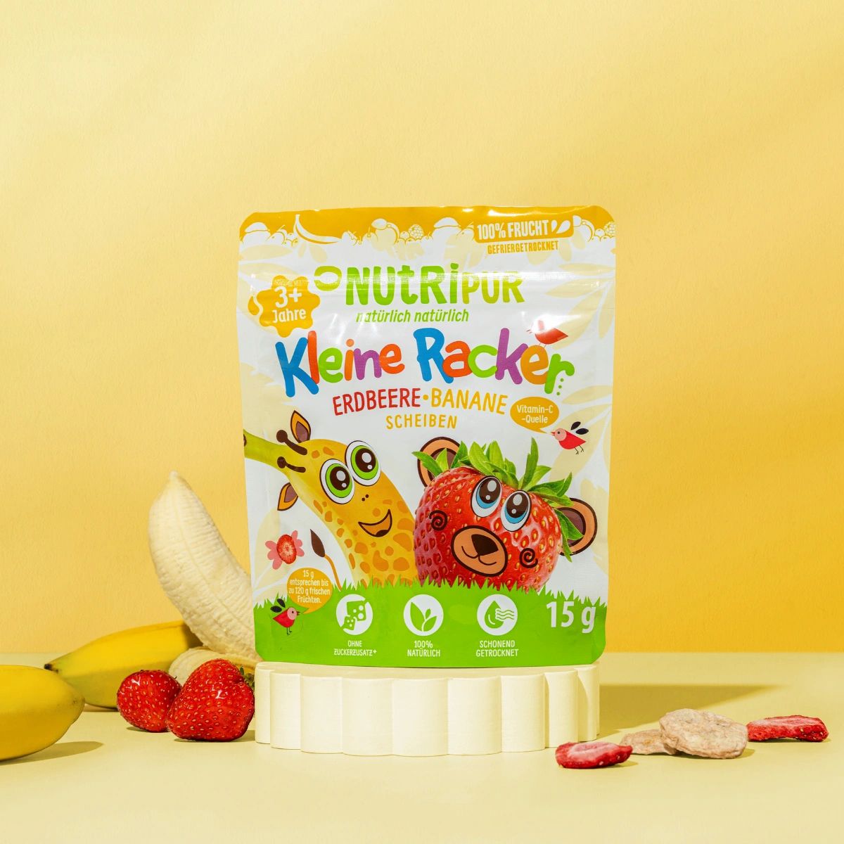 Verpackung mit gefriergetrockneten Früchten. Aufschrift: NutriPur, Kleine Racker Erdbeere-Banane. Abbildung von Giraffe und Erdbeer-Bär. Bananen und Erdbeeren.