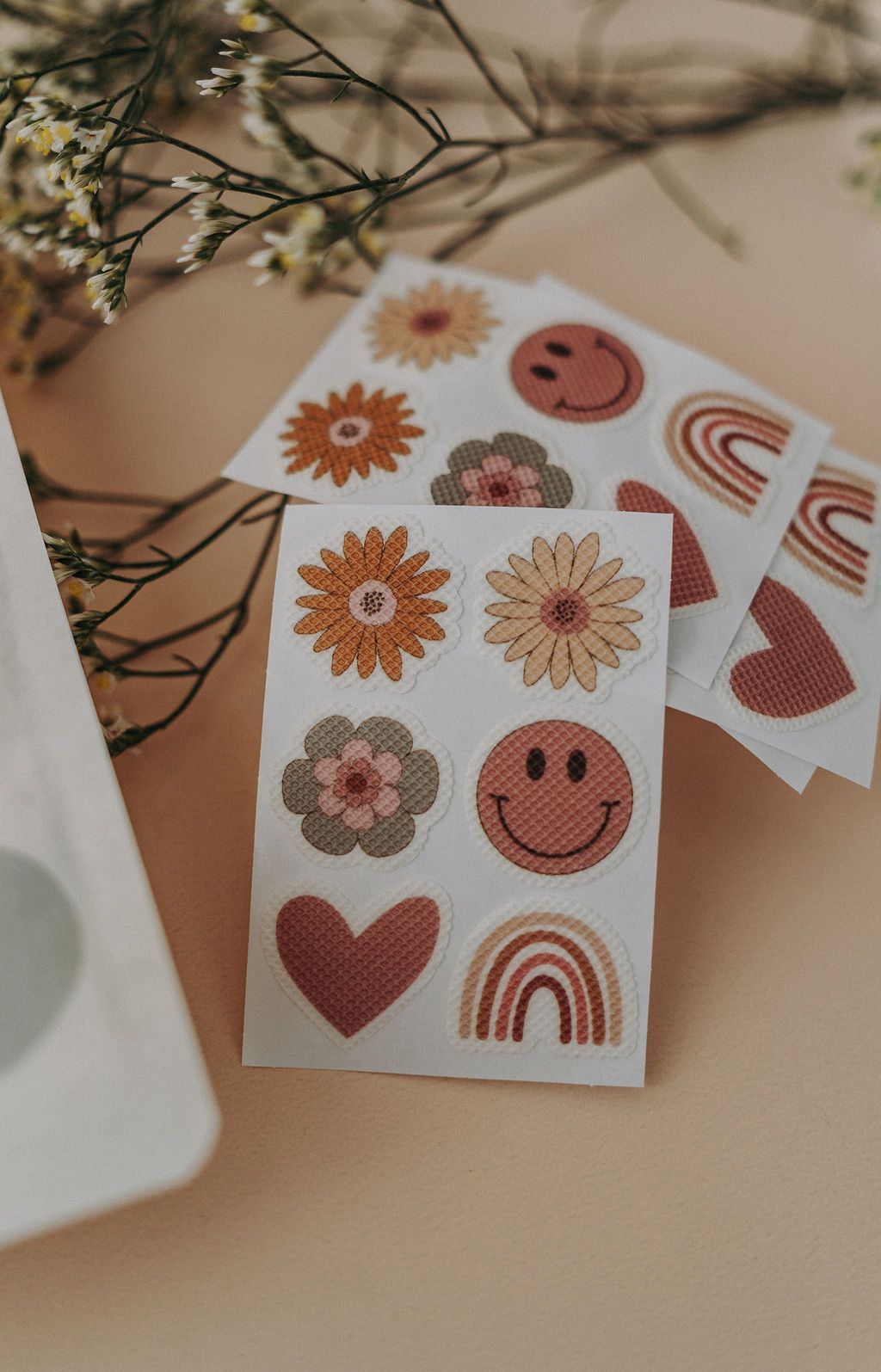 Mehrere Sticker mit Blumen-, Herz-, Regenbogen- und Smiley-Motiven. Auf weißem Hintergrund.