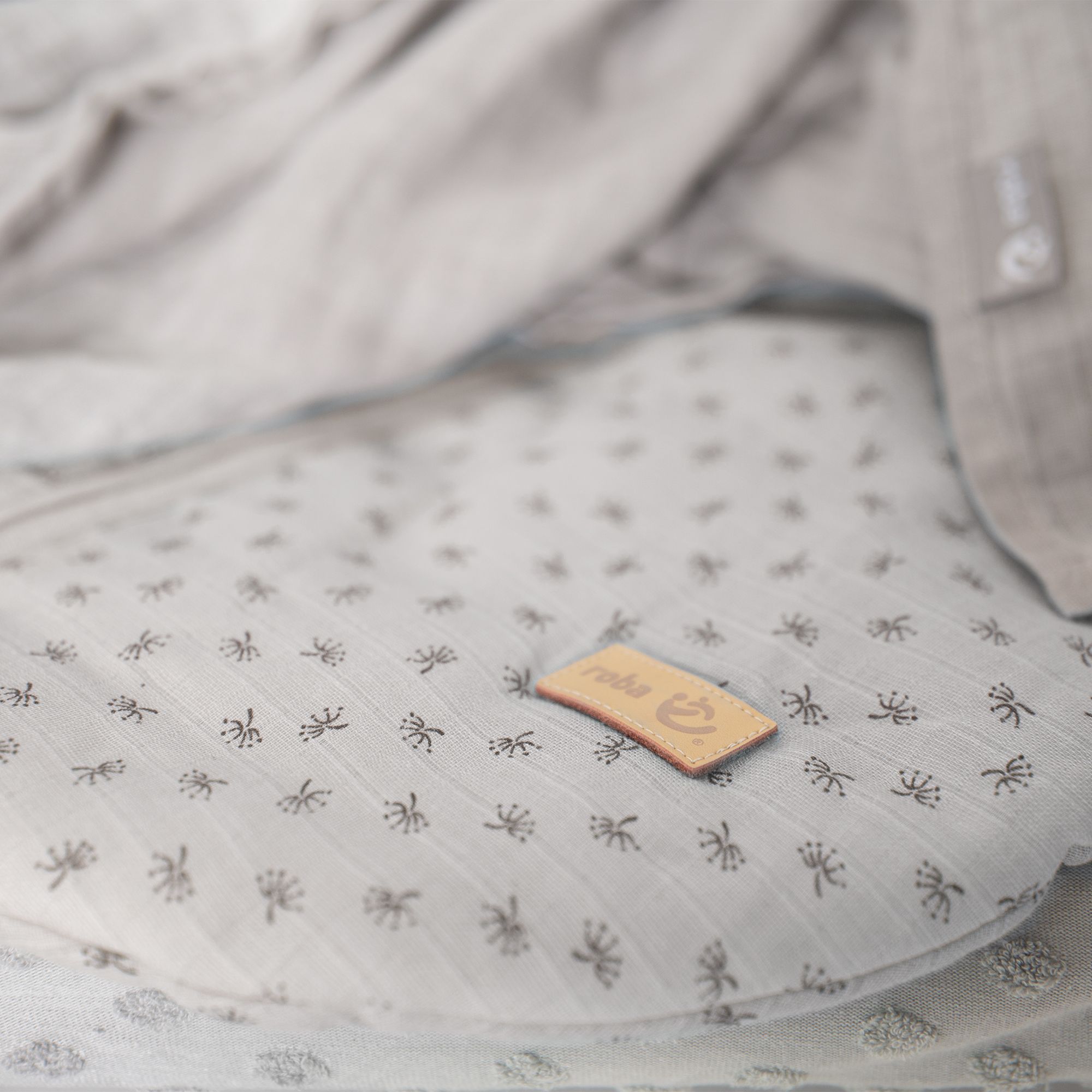Hellgrauer Schlafsack mit Muster. Kleines Lederetikett mit Logo.